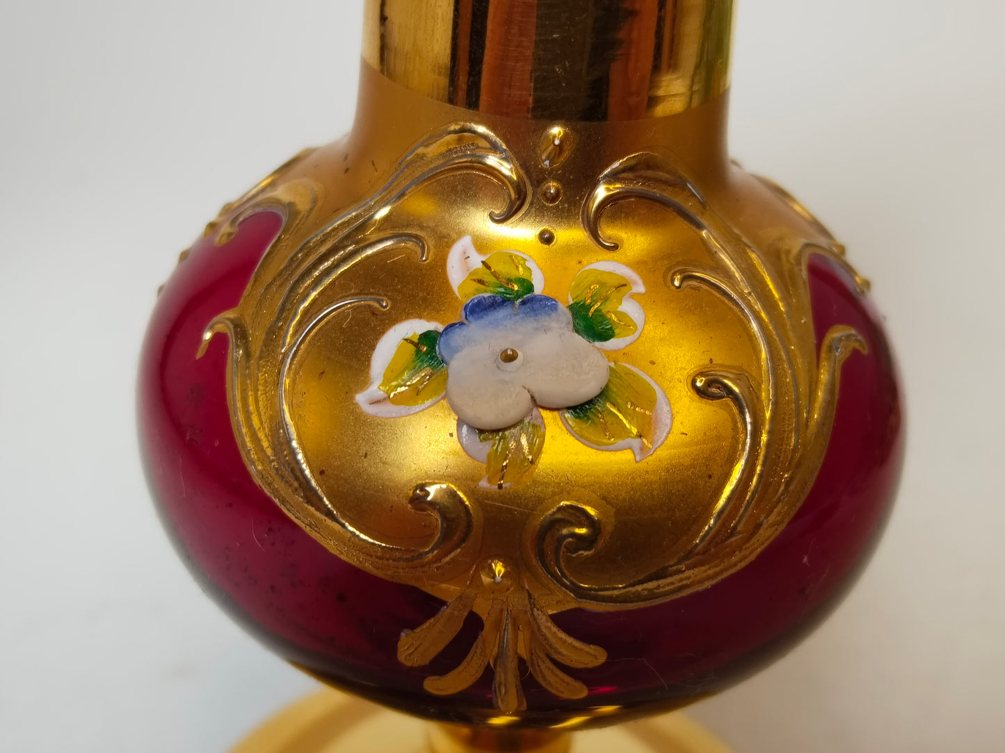 Detailaufnahme Bauch der Vase, erhabenes Gold-Rankwerk und Emaille-Blüte auf Weinrot
