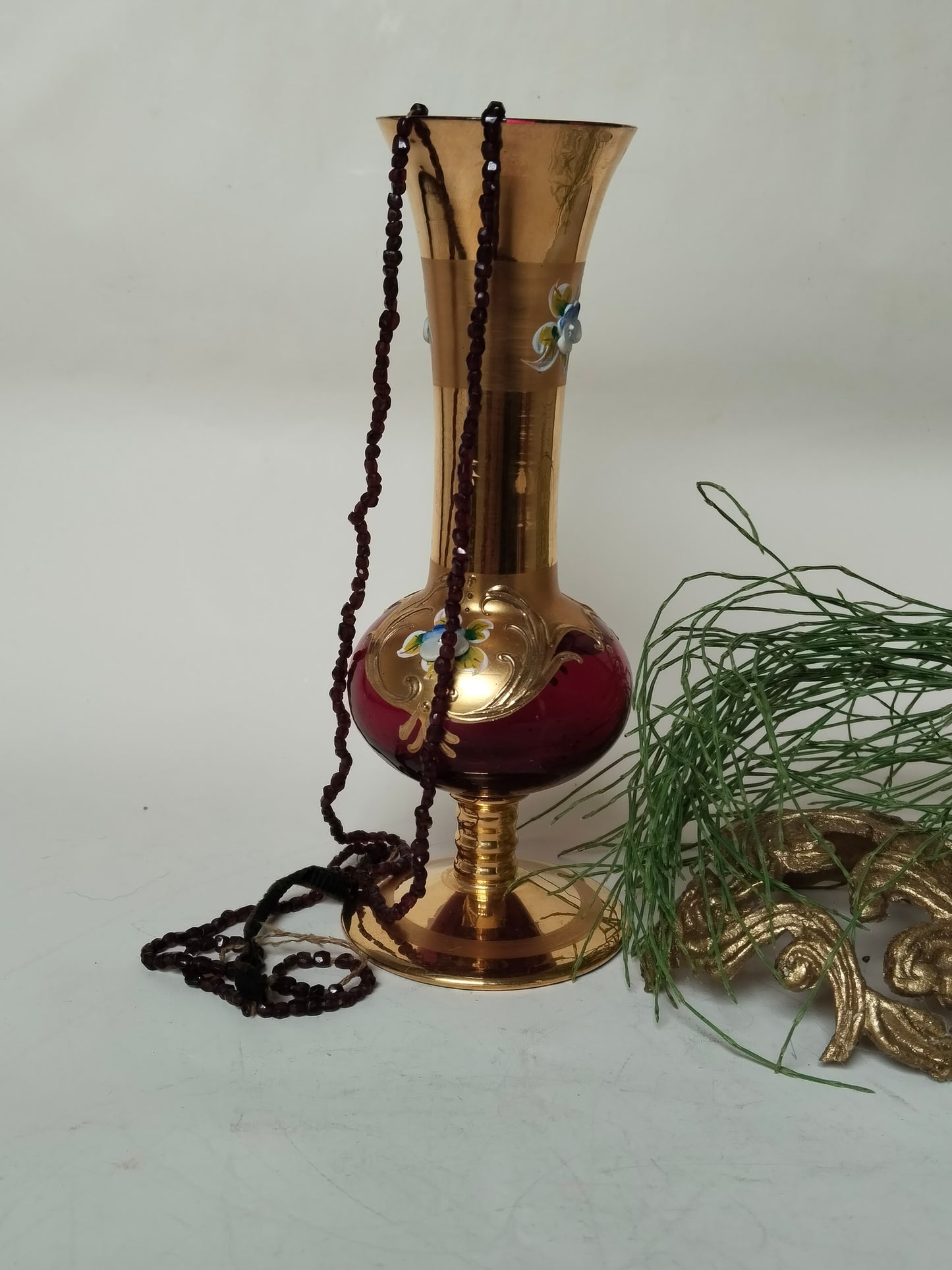 Böhmische Glasvase Rot-Gold seitlich gestylt mit Granatperlenkette und Tannenzweig
