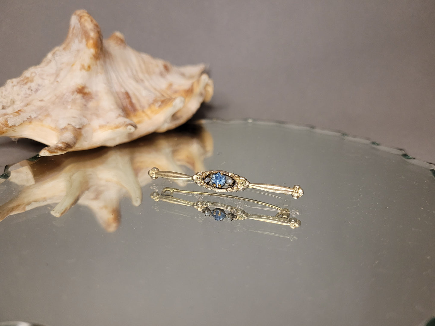 Edwardian Stabbrosche mit blauem Stein, neben einer dekorativen Muchel