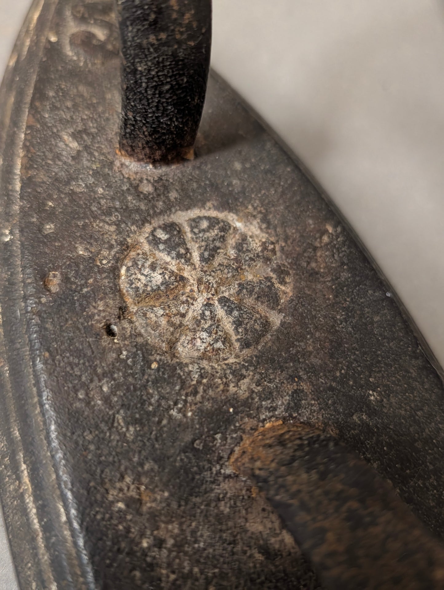 Makroaufnahme der floralen Rosetten-Gussmarke am Henkelansatz, Detail des antiken Gusseisen-Bügeleisens