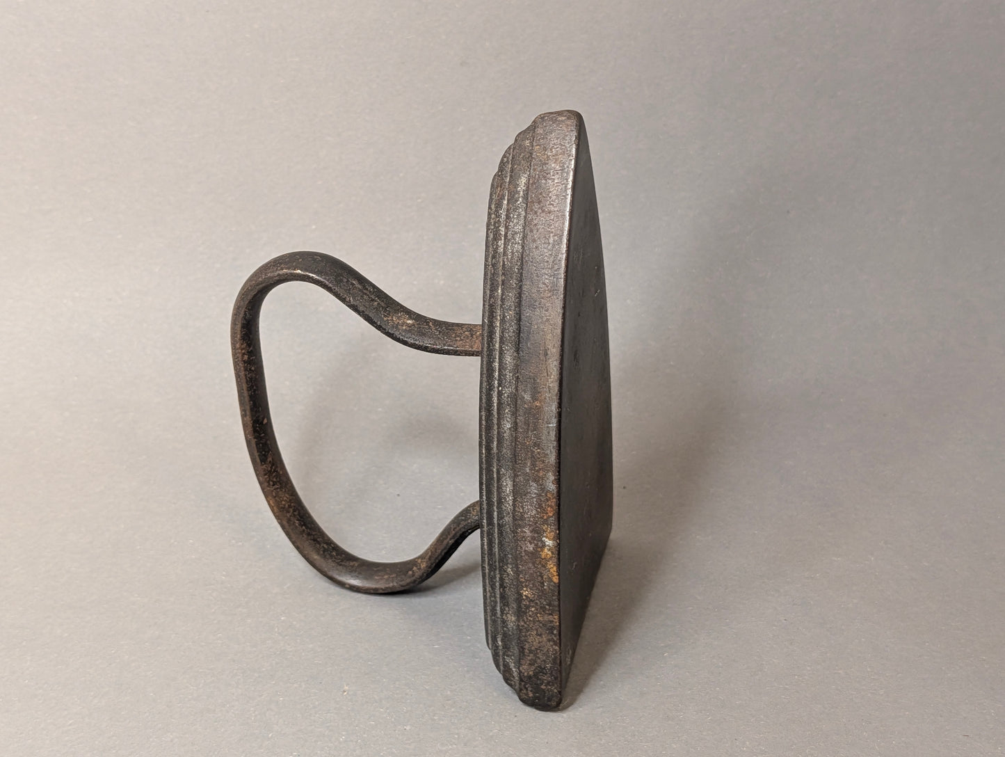 Seitenansicht des antiken Bügeleisens mit gestuftem Sohlenrand und Bügelhenkel, Gusseisen Vintage Deko