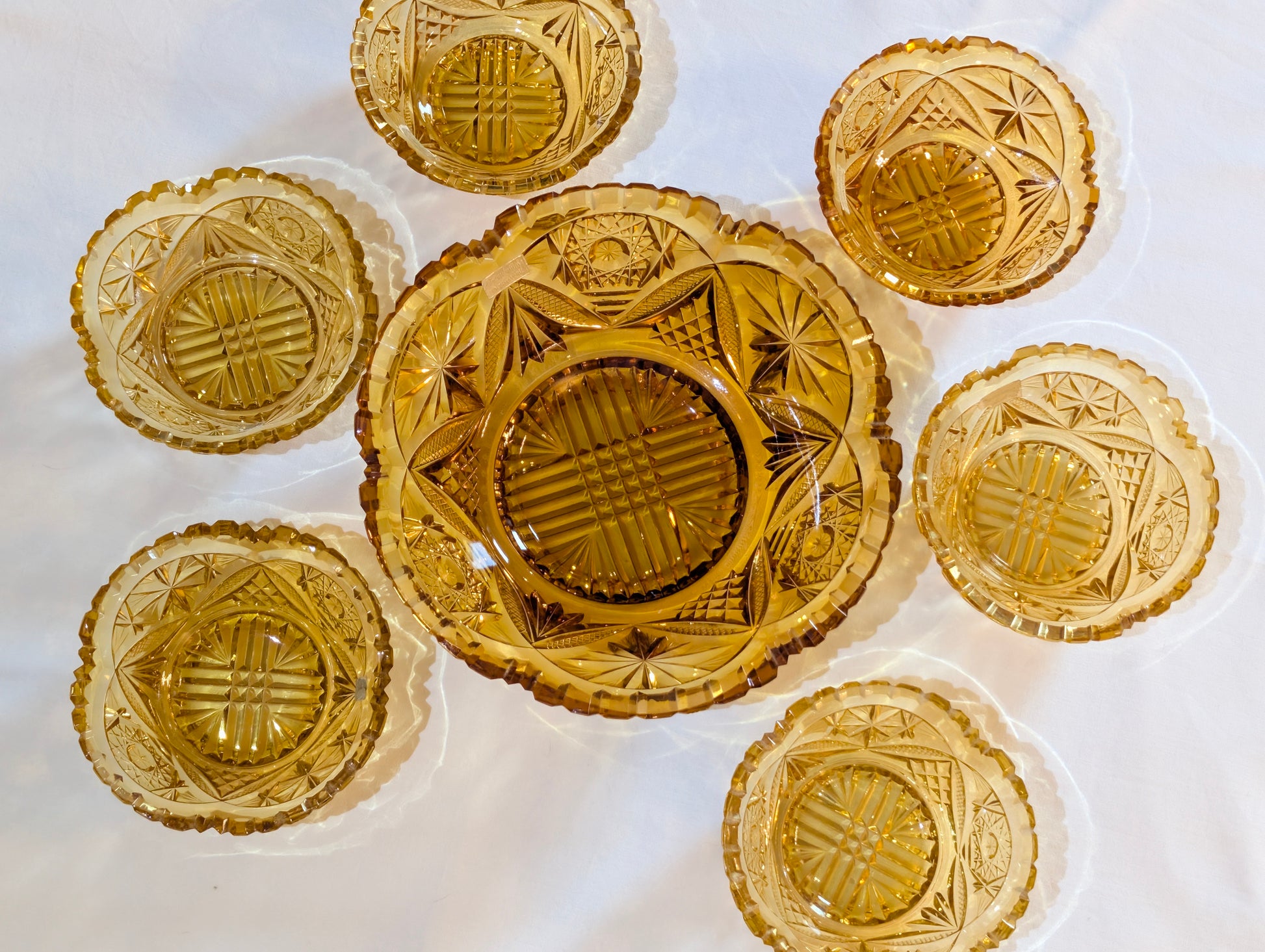 Sieben bernsteinfarbene Schliffglas-Schalen von oben arrangiert, Vintage Kristallglas-Set aus Österreich
