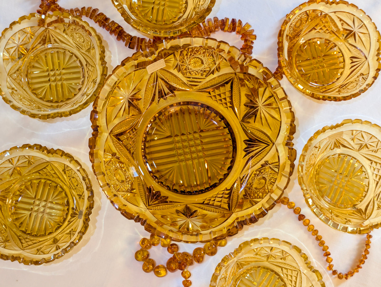 Bernsteinfarbenes Glas-Set mit Bernsteinkette dekoriert, Vintage Schliffglas amber, festliche Präsentation
