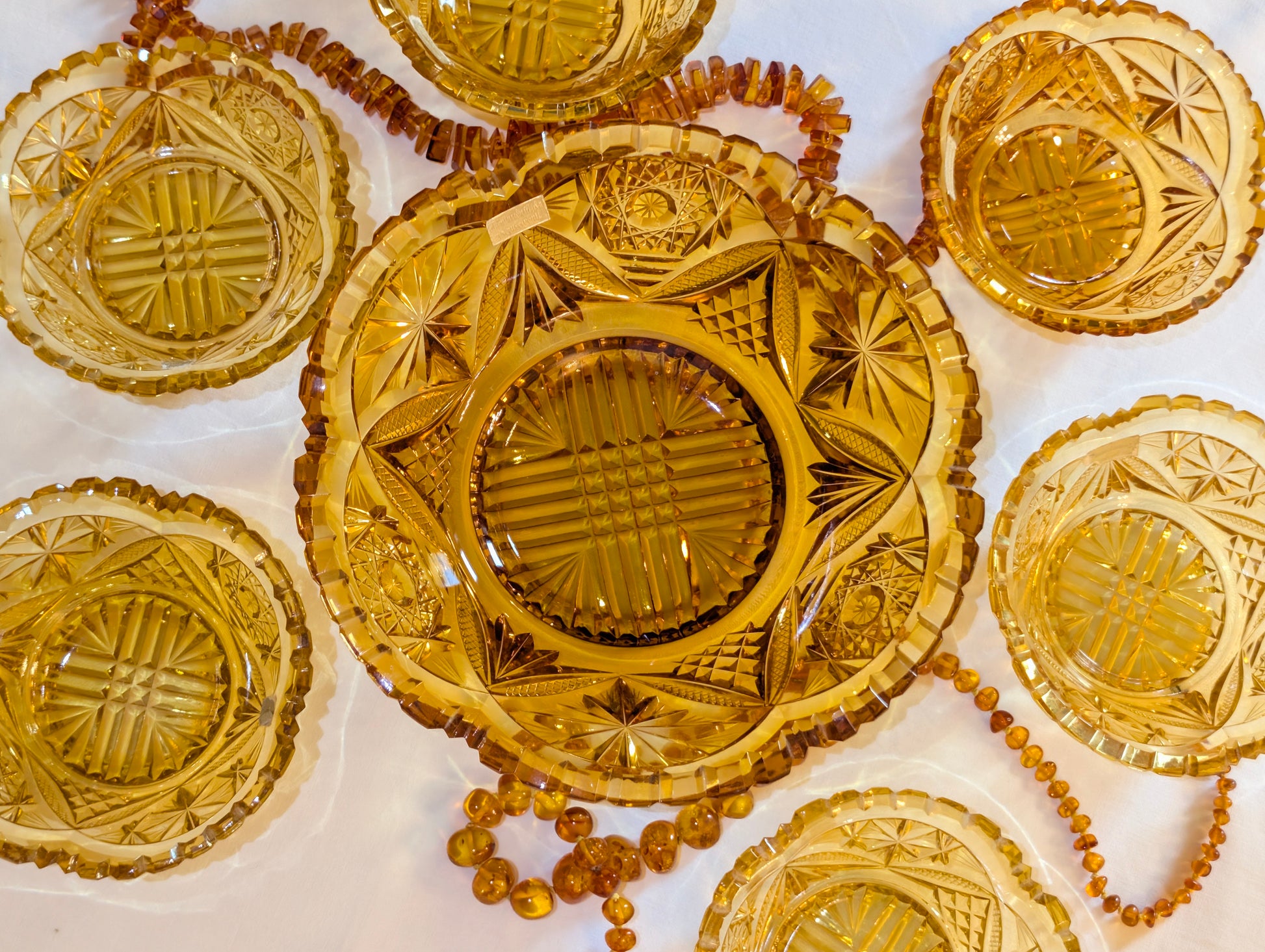 Bernsteinfarbenes Glas-Set mit Bernsteinkette dekoriert, Vintage Schliffglas amber, festliche Präsentation
