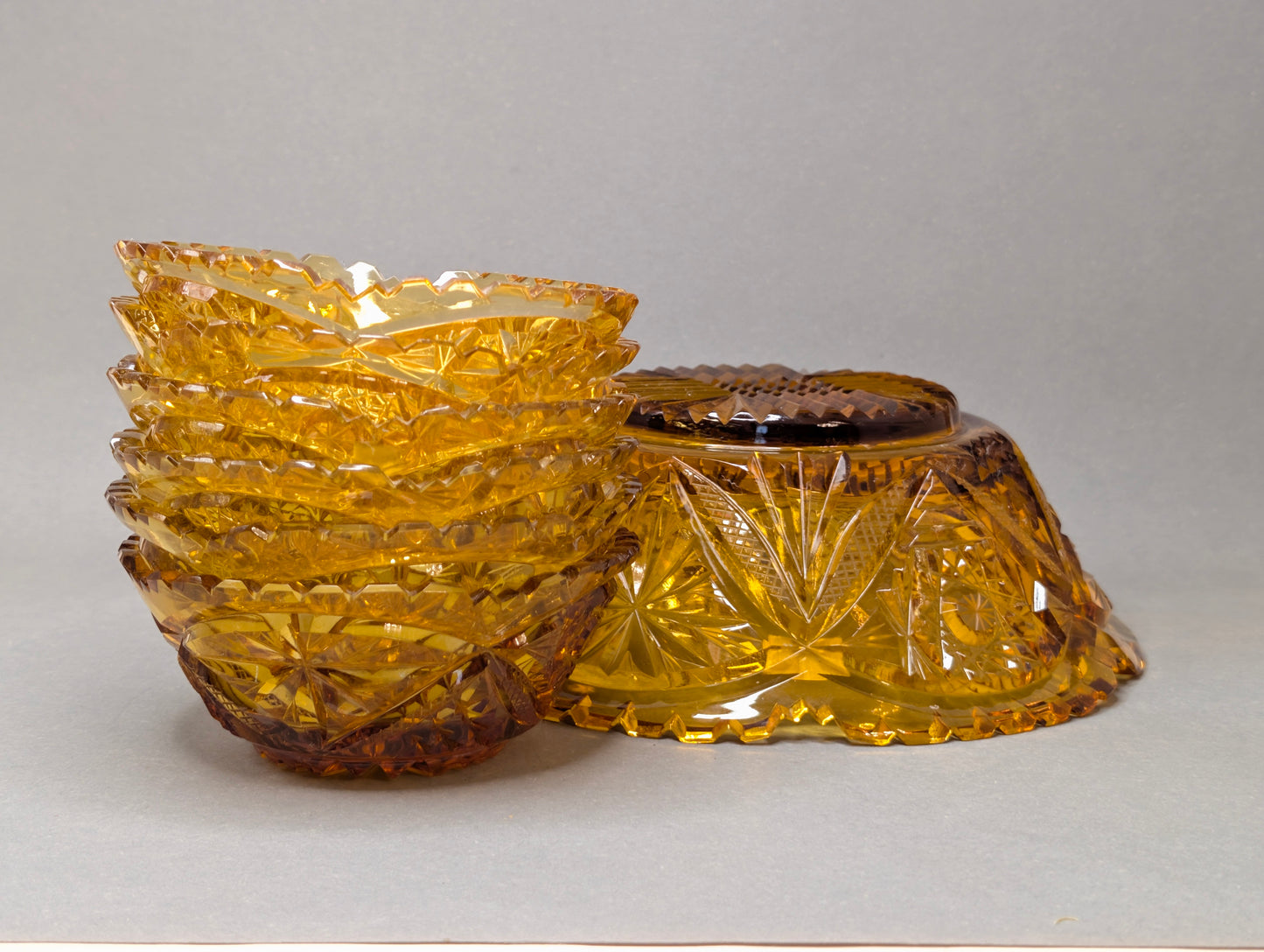 Gestapelte Bernstein-Schälchen neben großer Schliffschale, Sägezahnrand, Vintage Glas-Set amber
