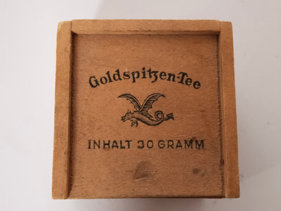 Deckel der Holz-Teedose mit Frakturschrift Goldspitzen-Tee, geflügeltem Drachen und Inhalt 30 Gramm
