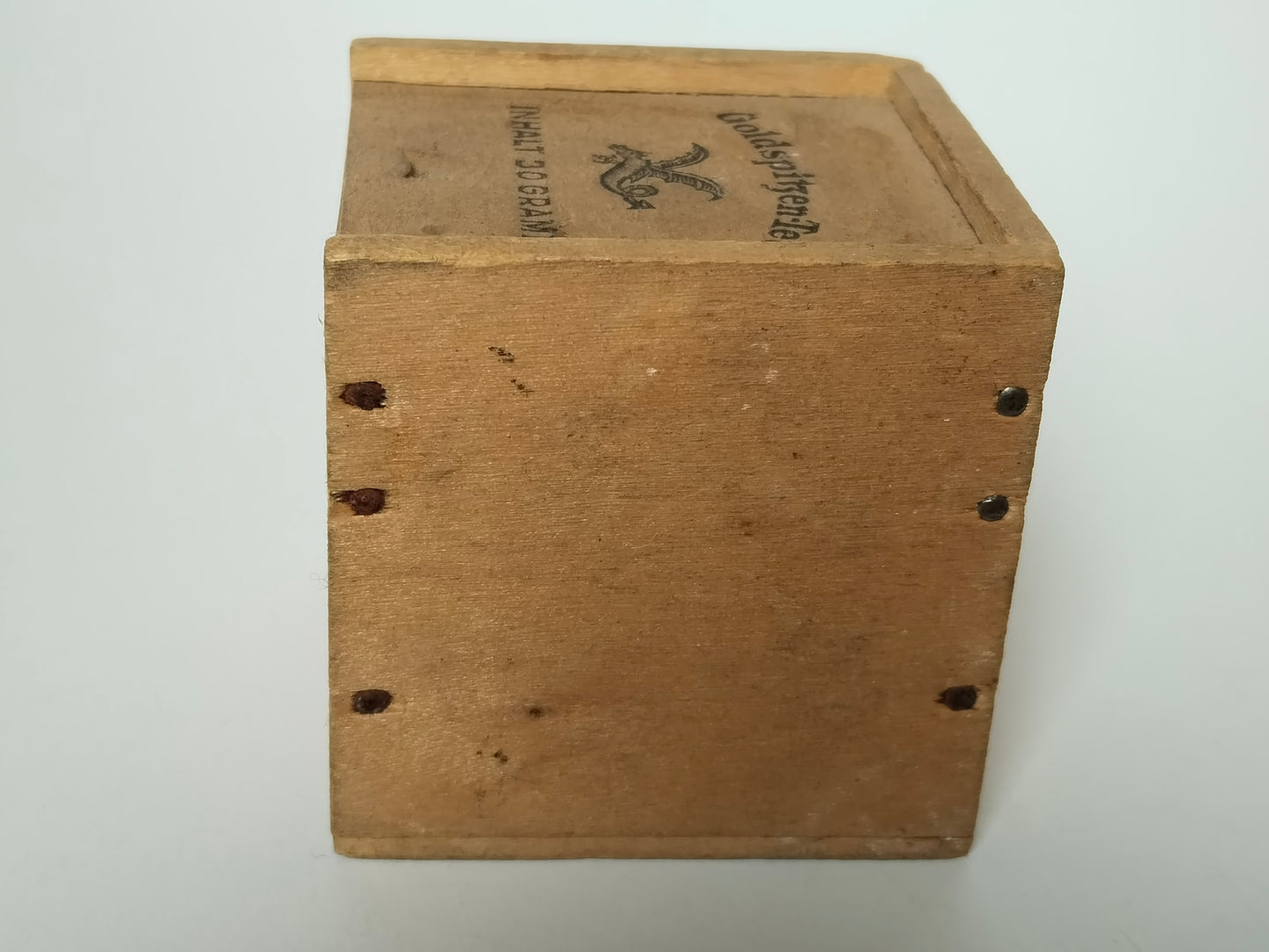 Seitenansicht der alten Teeschachtel aus Holz mit sichtbaren Eisenstiften an den Ecken
