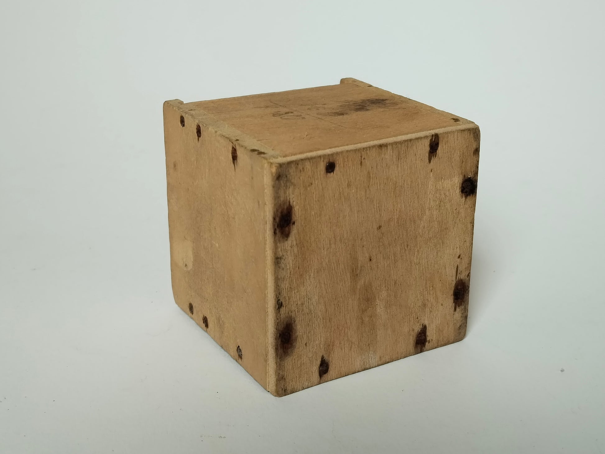 Boden der Teeschachtel aus Holz mit rostigen Eisenstiften und braunen Verfärbungen
