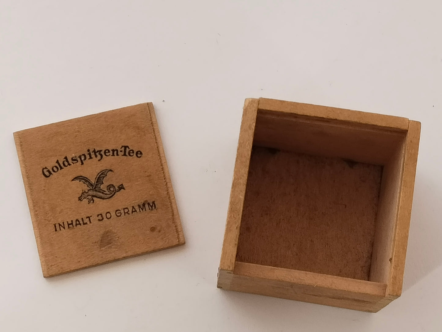 Abgenommener Deckel neben dem leeren Holzkästchen, Drachenmarke gut sichtbar
