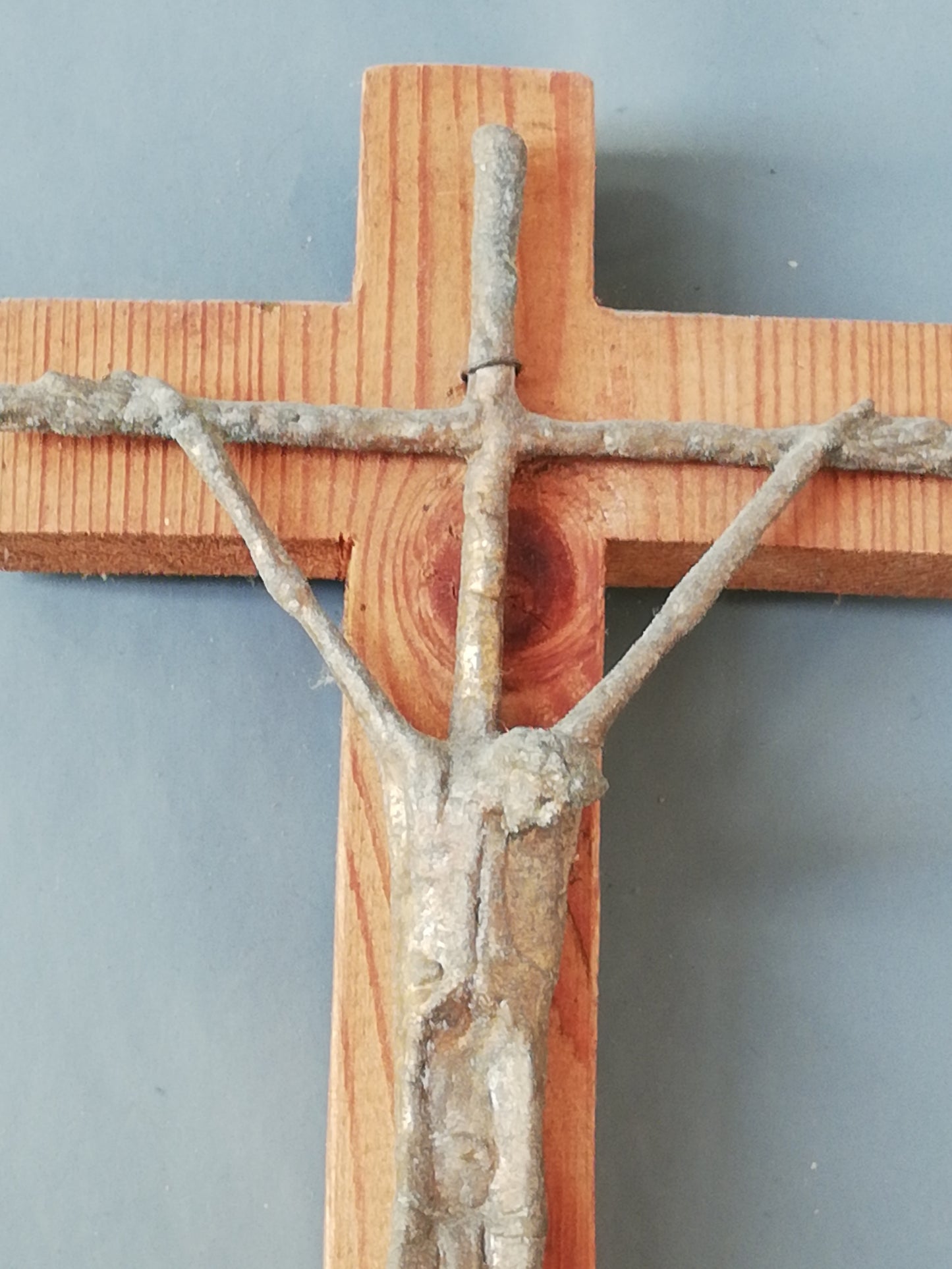 Handgeschnitztes Holzkreuz mit Christus. Oberer Teil des Kreuzes in Nahaufnahme.
