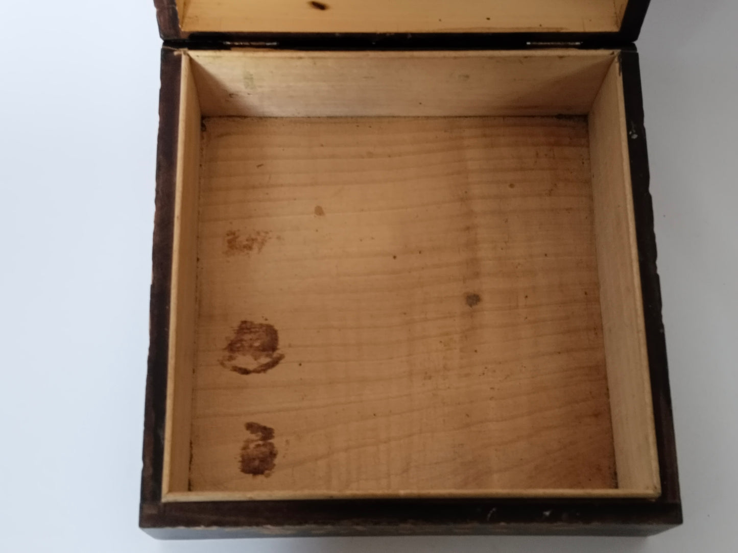 Innenraum der Holzschatulle von oben mit hellem Holzboden und alten Gebrauchsspuren
