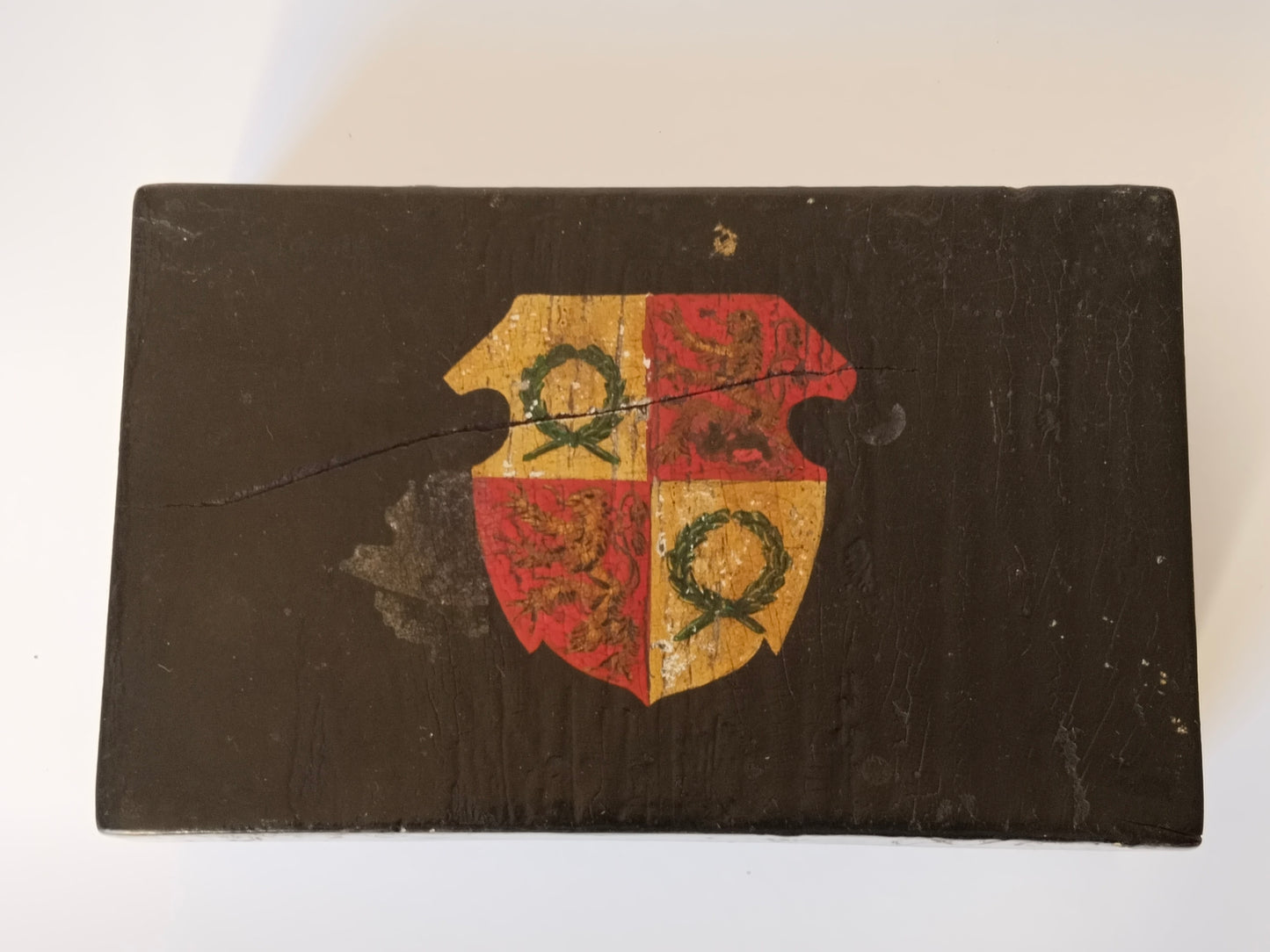 Draufsicht auf das handgemalte Wappen, gevierter Schild in Rot und Gold auf schwarzem Lack
