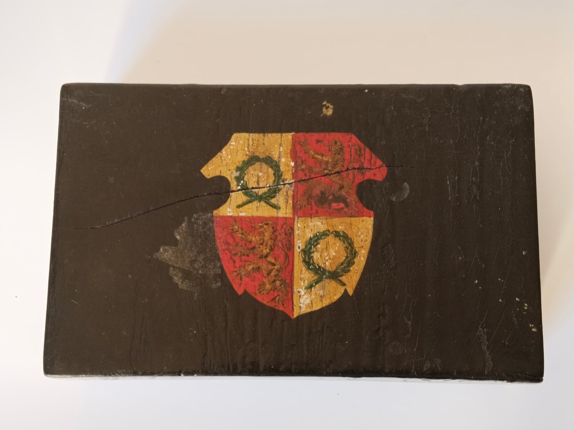 Draufsicht auf das handgemalte Wappen, gevierter Schild in Rot und Gold auf schwarzem Lack
