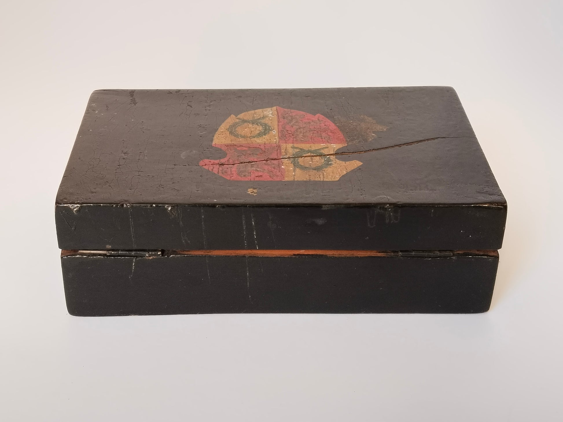 Schwarze Wappen-Schatulle aus Holz, Frontansicht mit Deckelspalt und Messingscharnier
