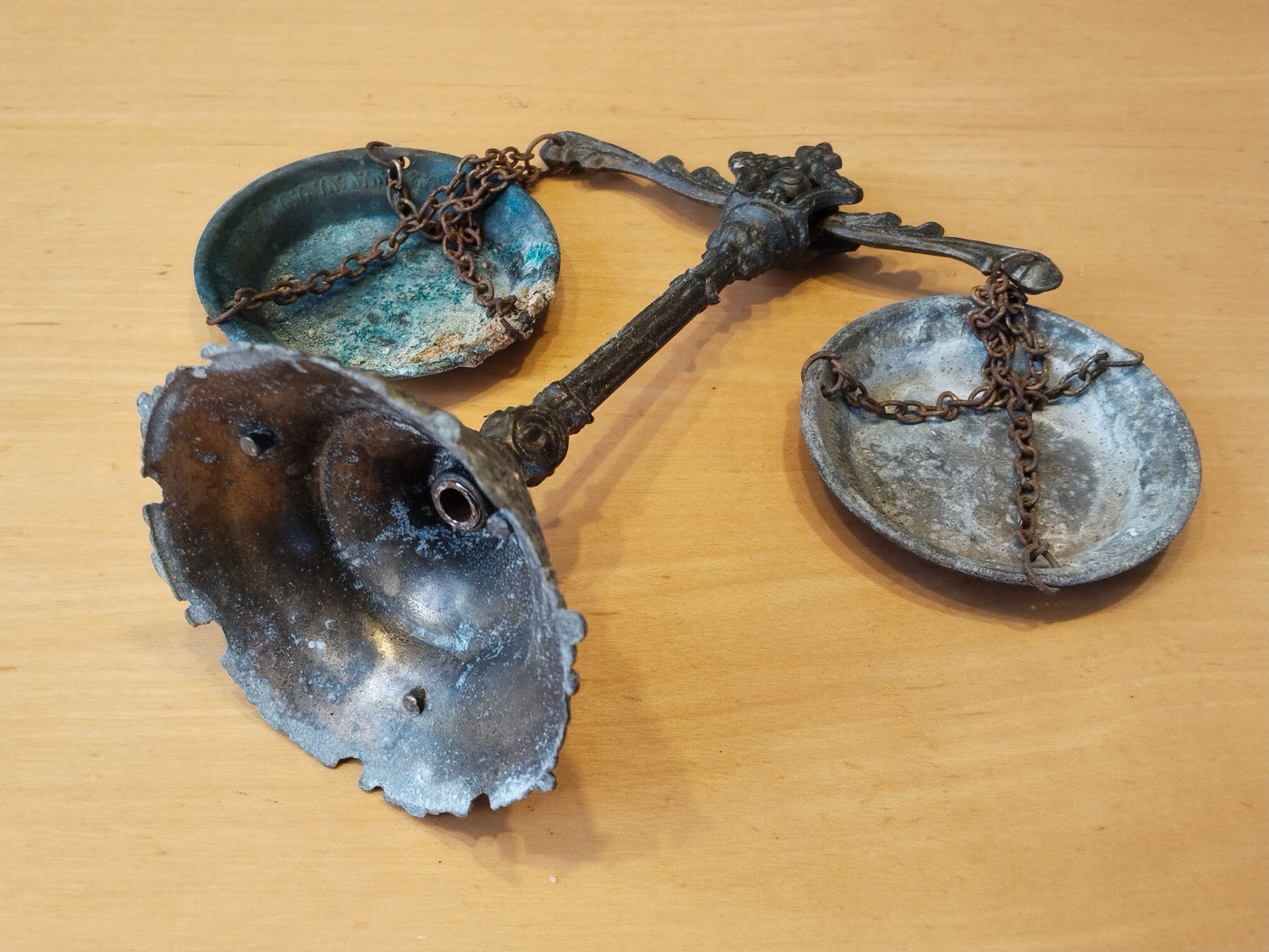 Antike Balkenwaage aus Gussmetall mit zwei Schalen an Eisenketten, Gesamtansicht liegend.
