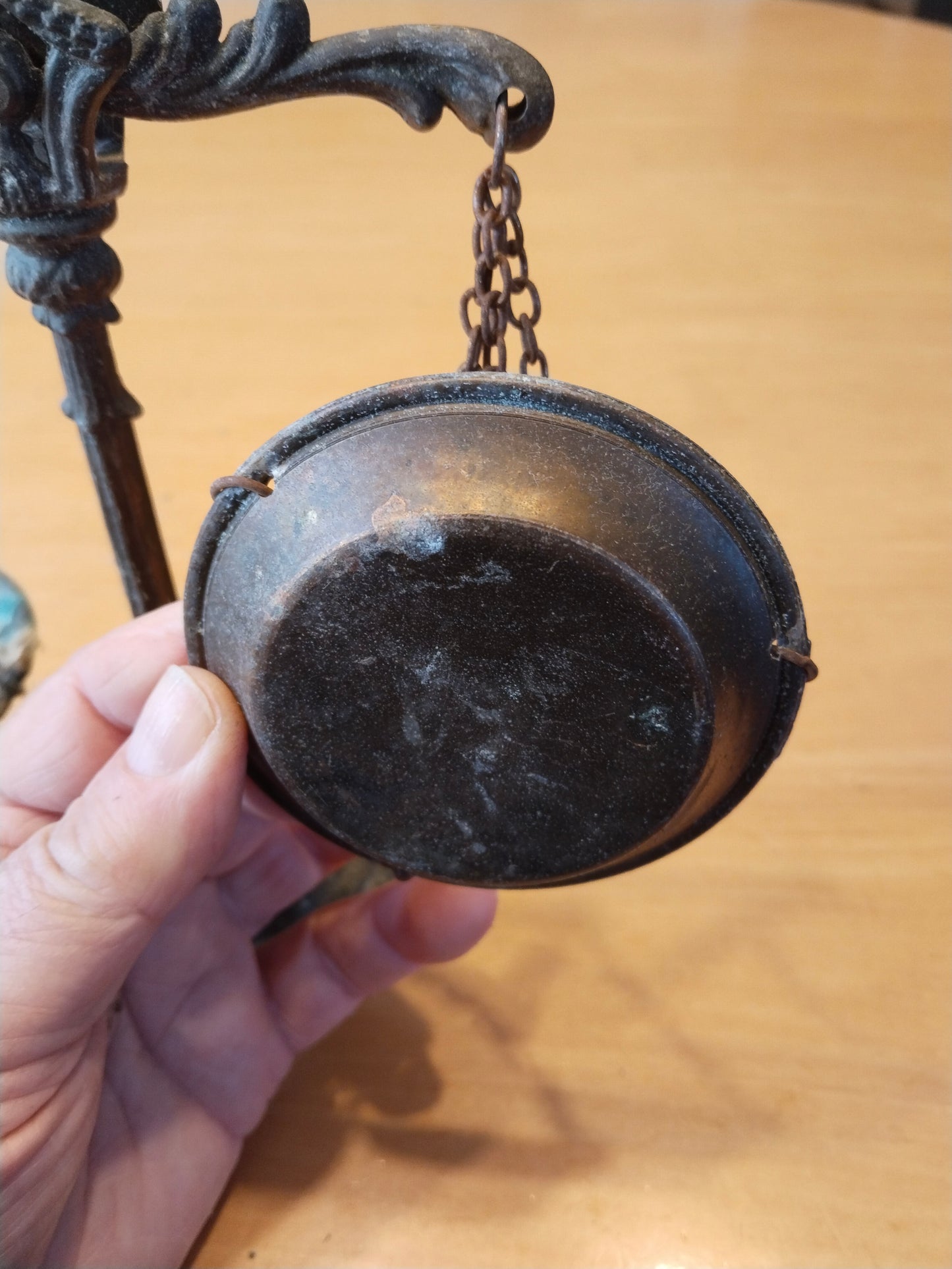 Antike Balkenwaage aus Gussmetall mit zwei Schalen an Eisenketten, Ansicht rechte Schale von unten.
