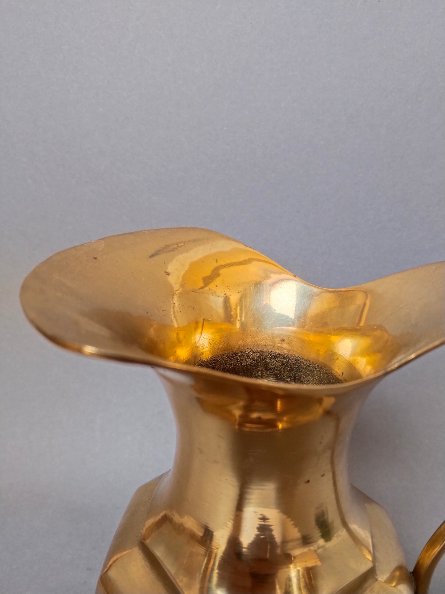Nahaufnahme der Tülle und des elegant geschwungenen oberen Randes der goldenen Kanne