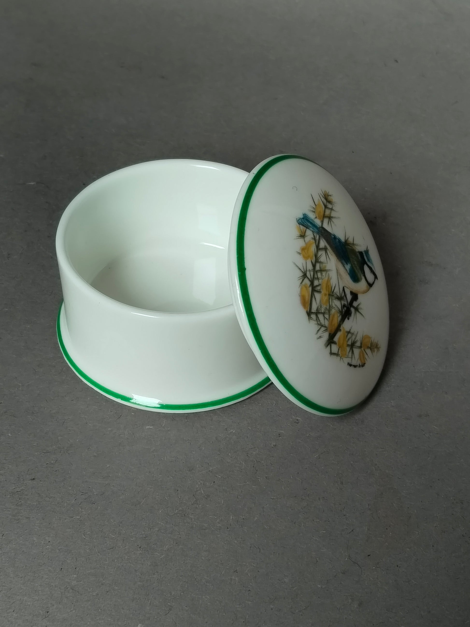 Die geöffnete, leere Dose steht neben dem umgedrehten Deckel auf grauem Untergrund.