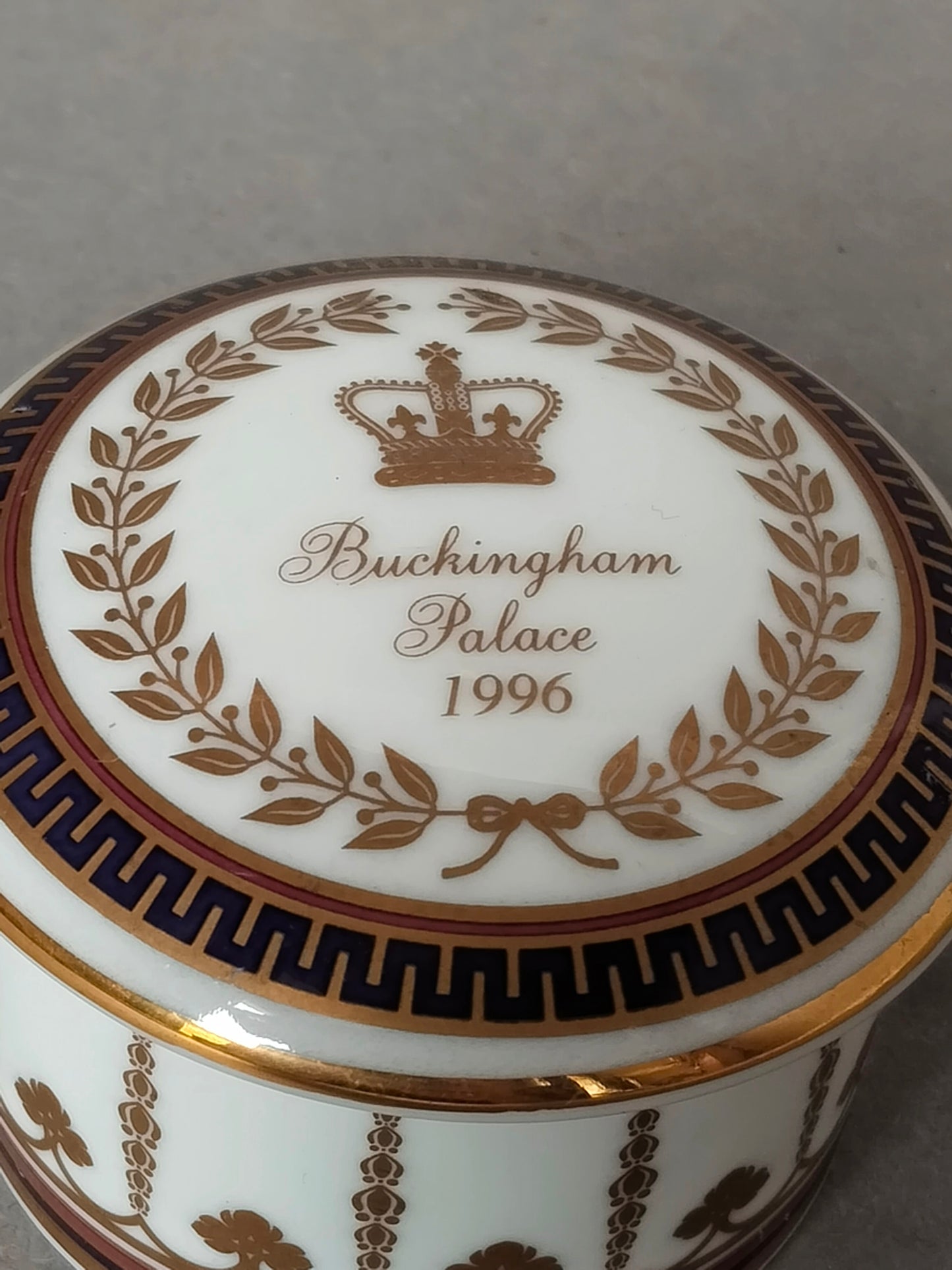 Draufsicht auf den Deckel der Dose mit der Aufschrift Buckingham Palace 1996 und einer goldenen Krone im Lorbeerkranz