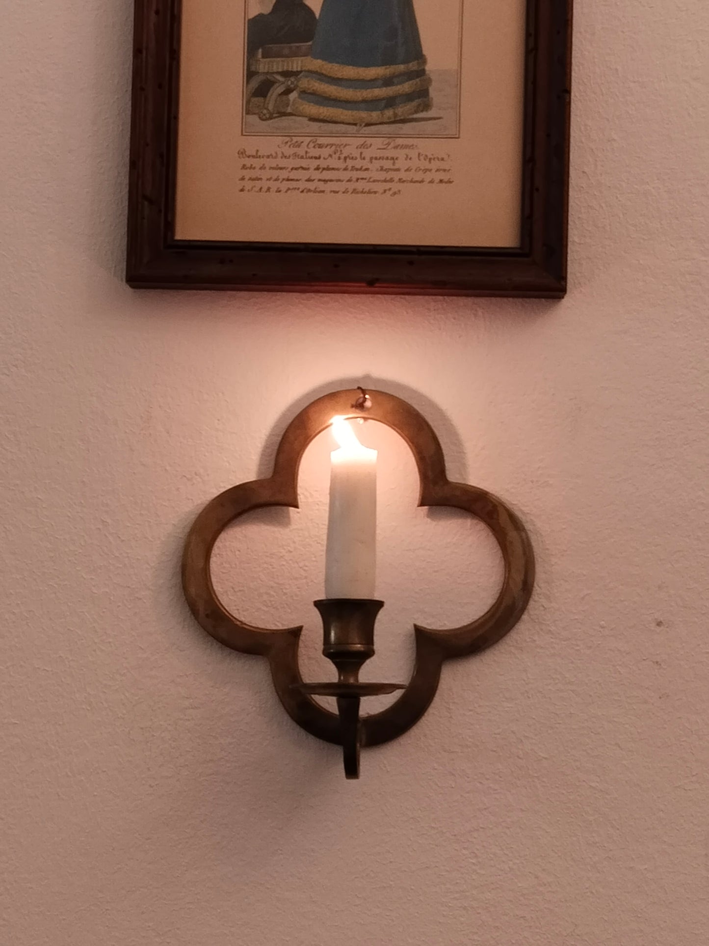 Historischer Wandleuchter aus Messing im Vierpass-Design an einer weißen Wand