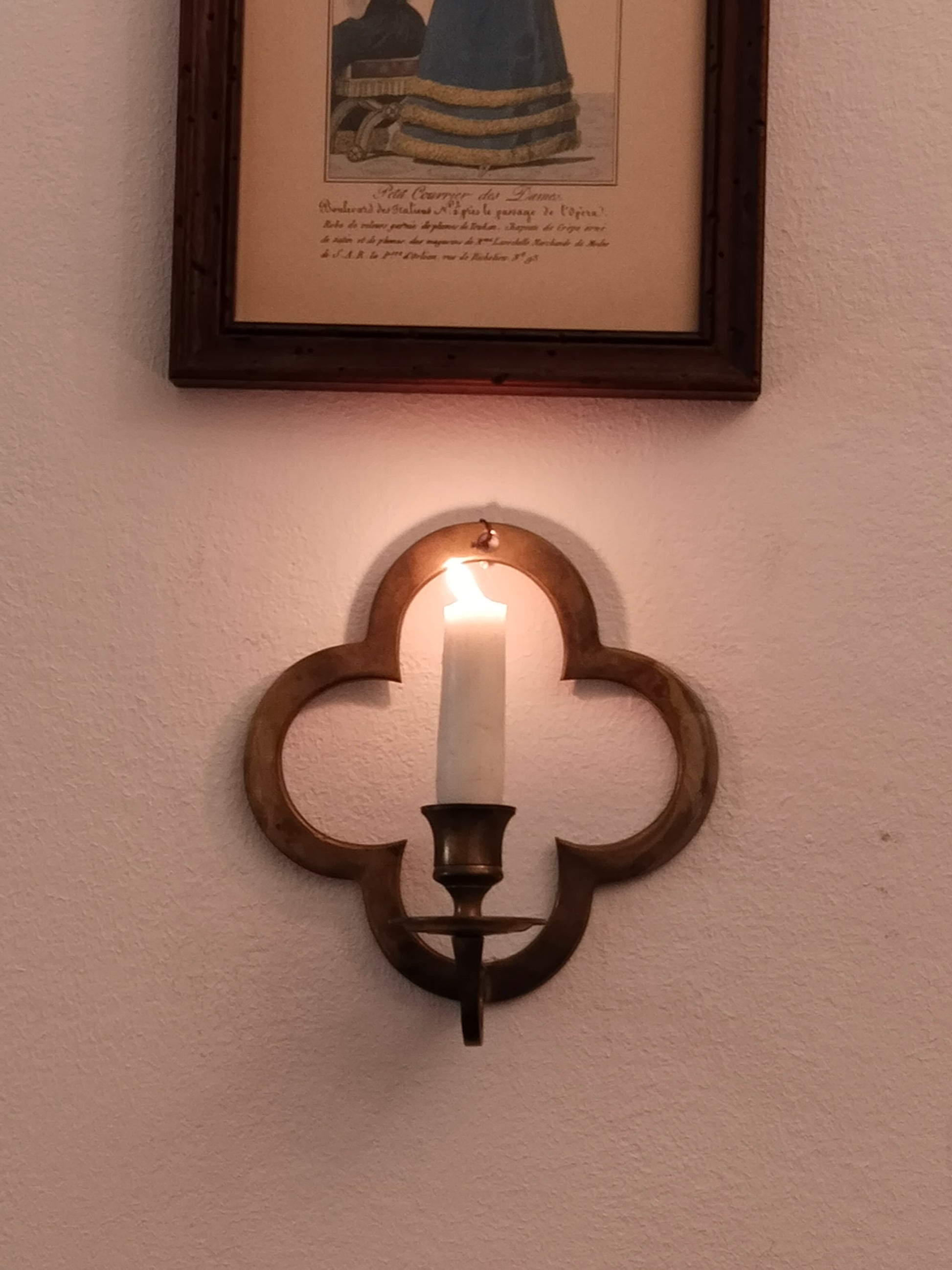 Historischer Wandleuchter aus Messing im Vierpass-Design an einer weißen Wand