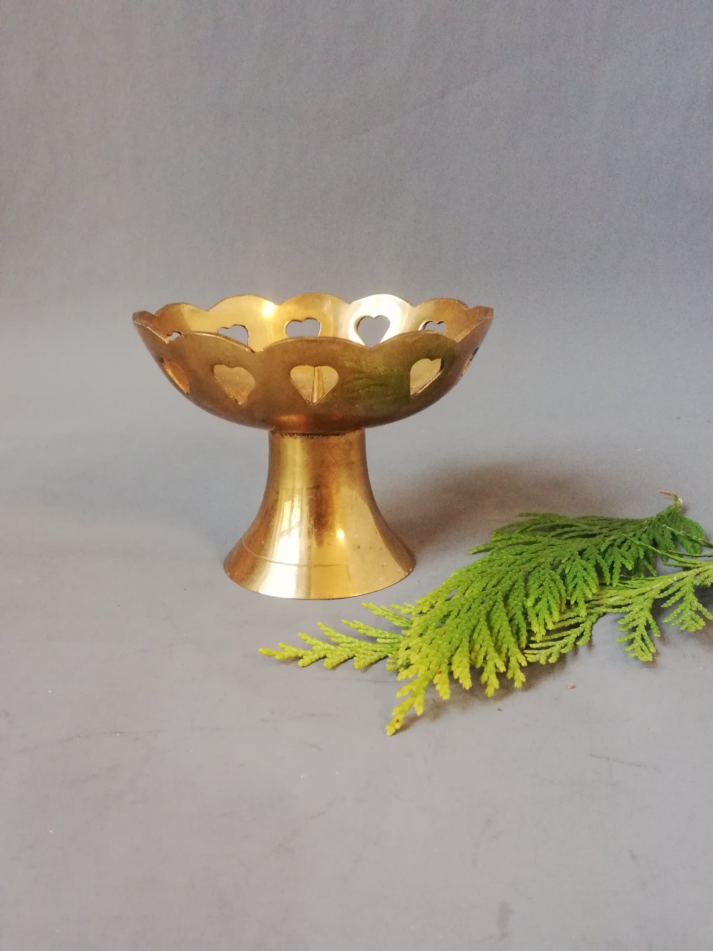 Kleiner Vintage Messing Kerzenständer mit eingestanzten Herzen neben Dekozweig.