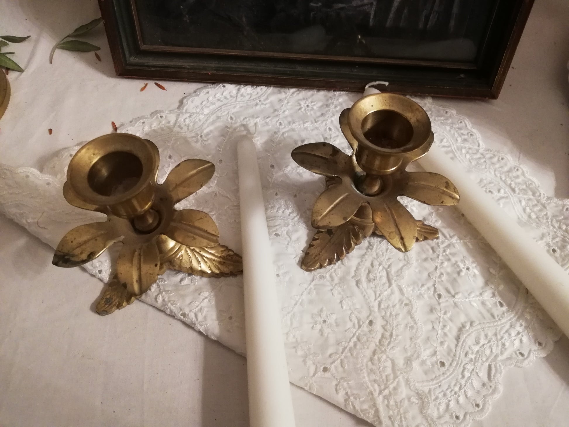Zwei antike Messing-Kerzenständer mit Akanthusblatt-Fuß auf weißer Spitzendecke. Ansicht von oben.
