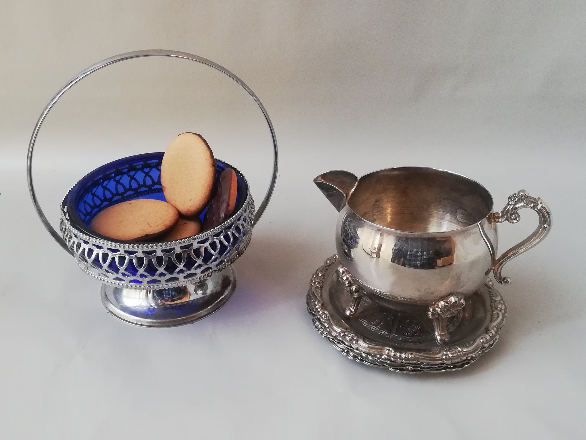 Vintage Glasschale blau mit versilbertem Rahmen mit Konfekt und einem Milchkännchen.