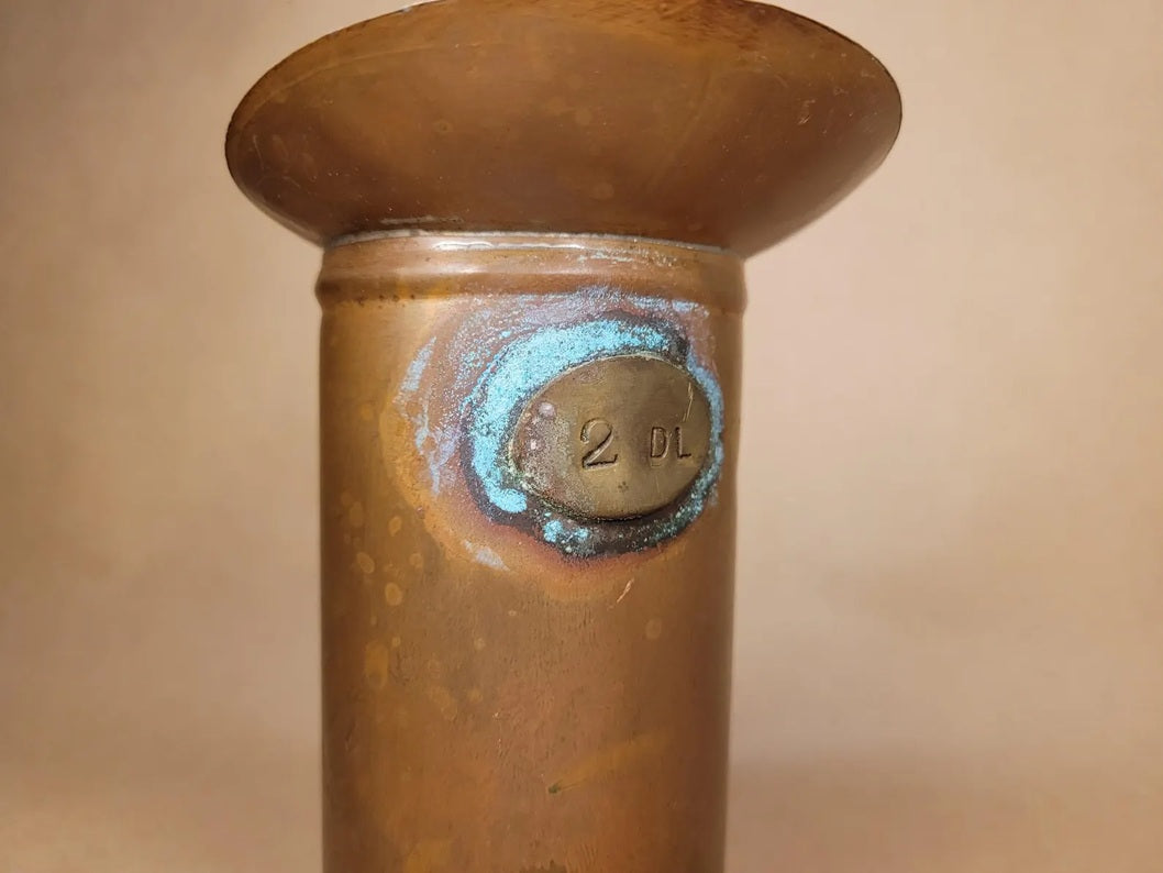 Detailaufnahme des Messing-Siegels mit der Gravur "2 DL" und türkisfarbener Patina.
