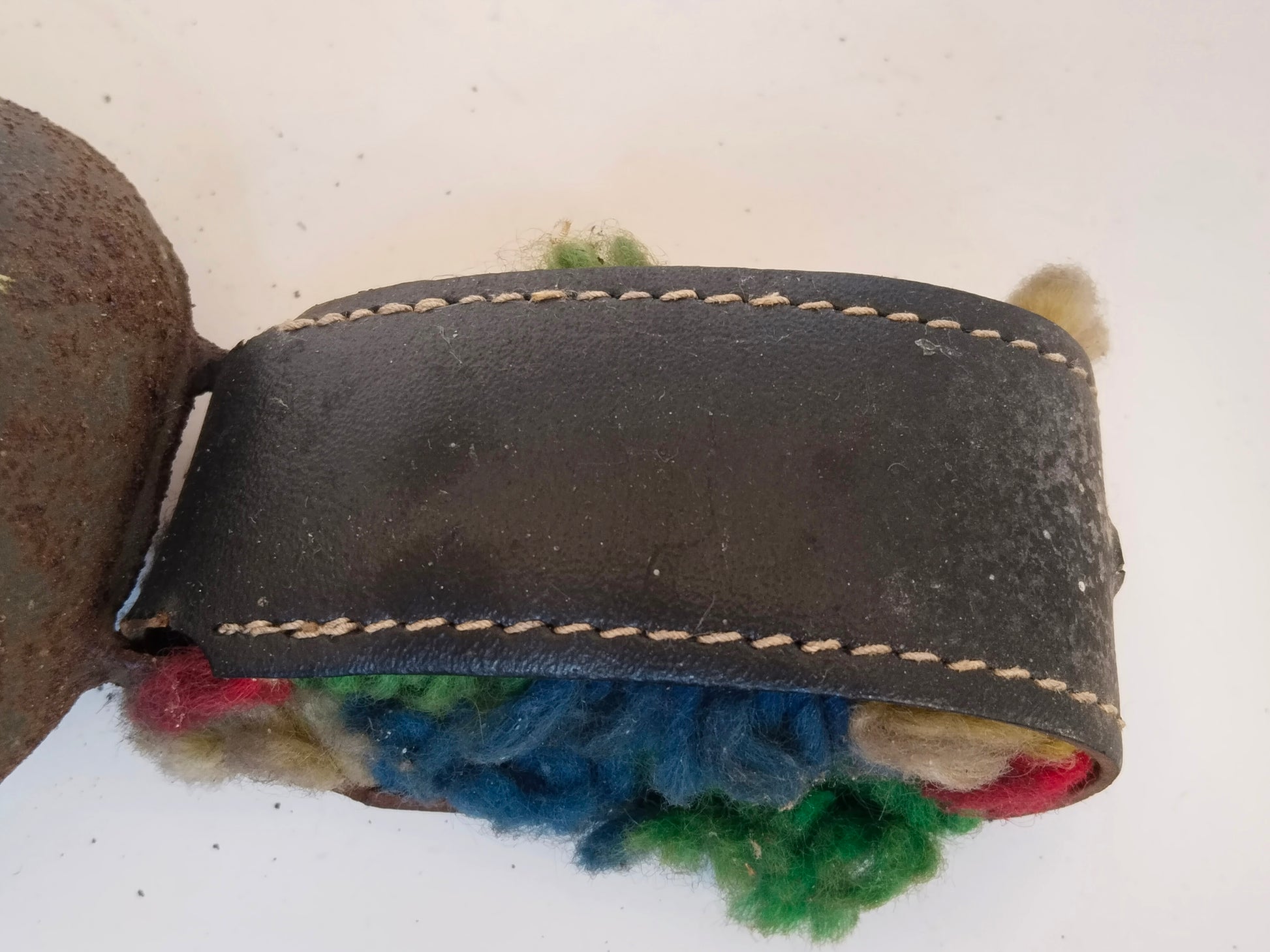 Geschlossene Lederschlaufe mit Blick auf bunte Wollfäden im Inneren
