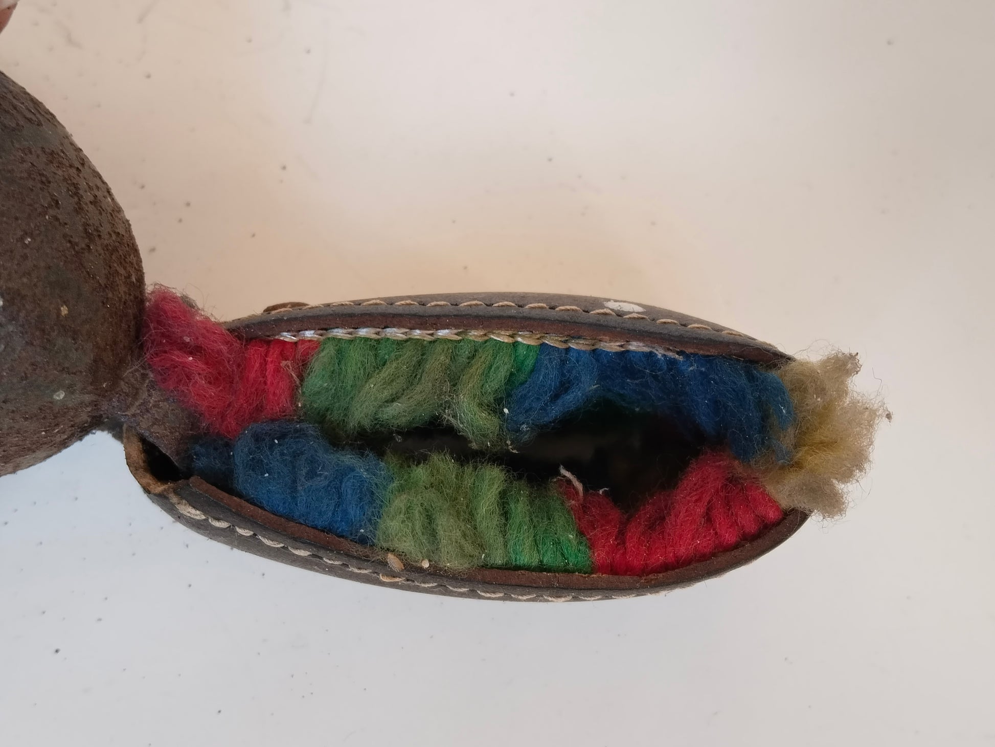 Geschlossene Lederschlaufe mit Blick auf bunte Wollfäden im Inneren
