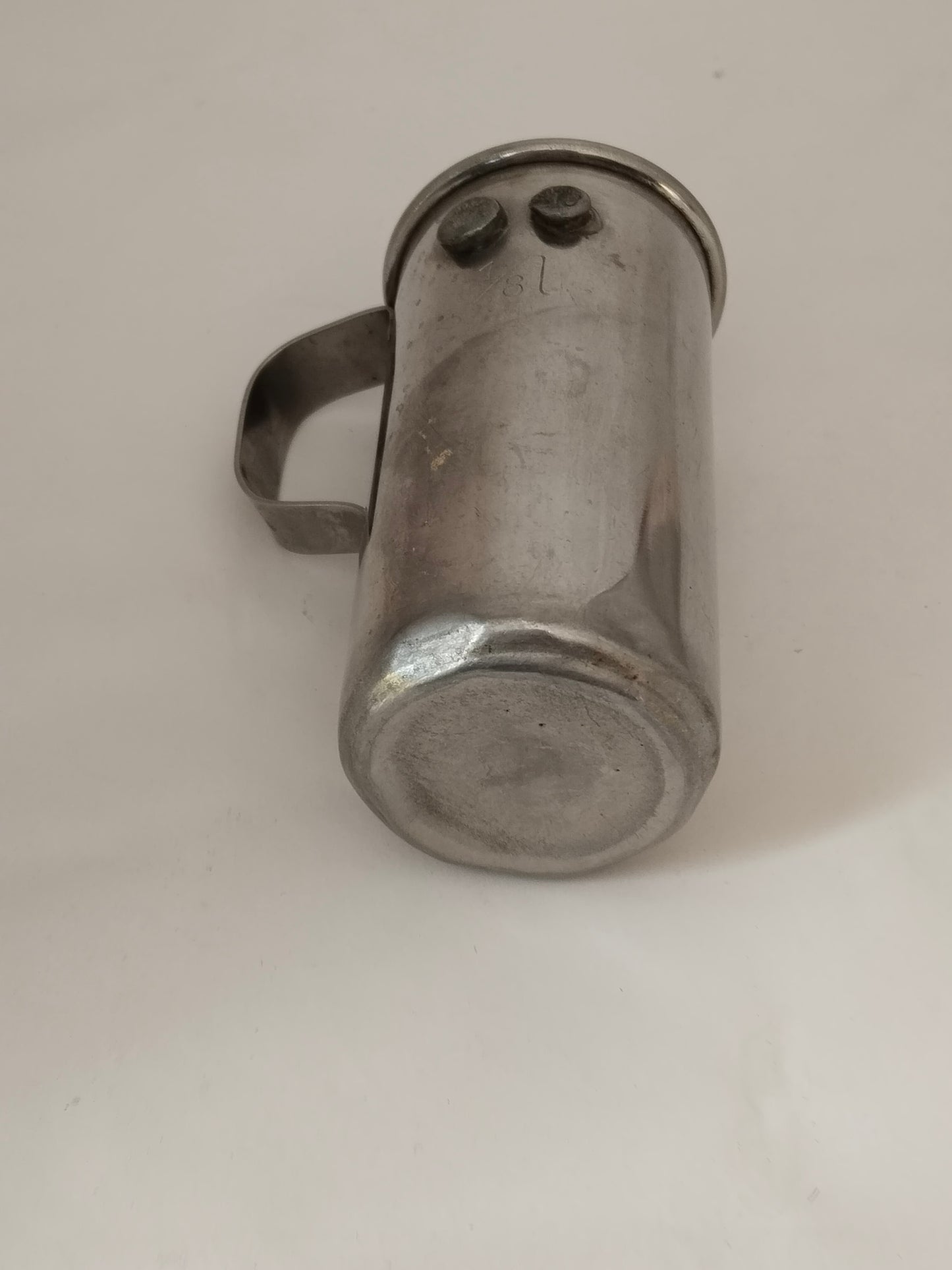 Antiker Messbecher 1/8 Liter Ideal Austria, liegende Ansicht mit Sicht auf den Boden.