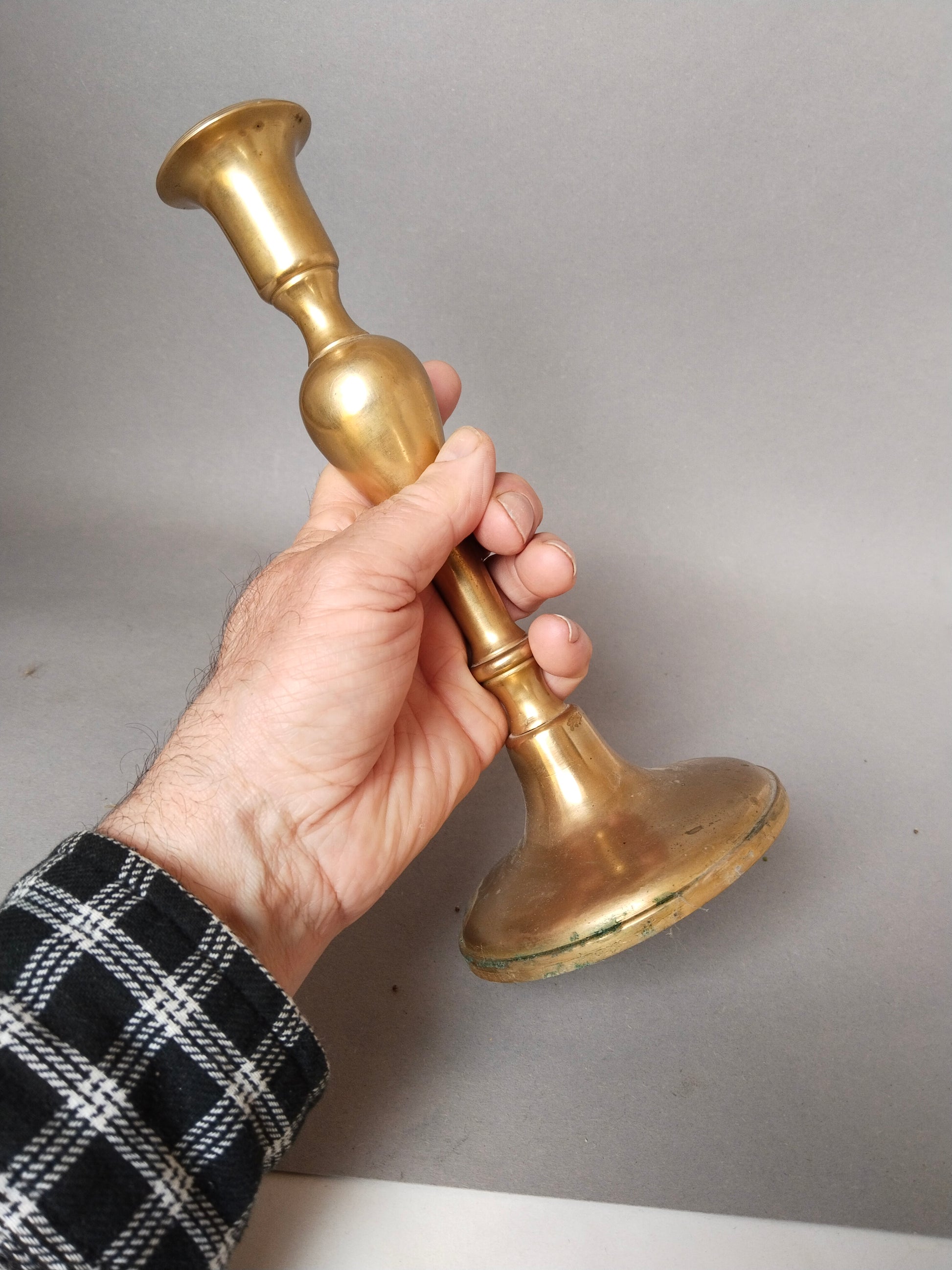 Klassischer Tafelleuchter aus schwerem Glockenmessing edler Goldglanz in einer Hand gehalten.