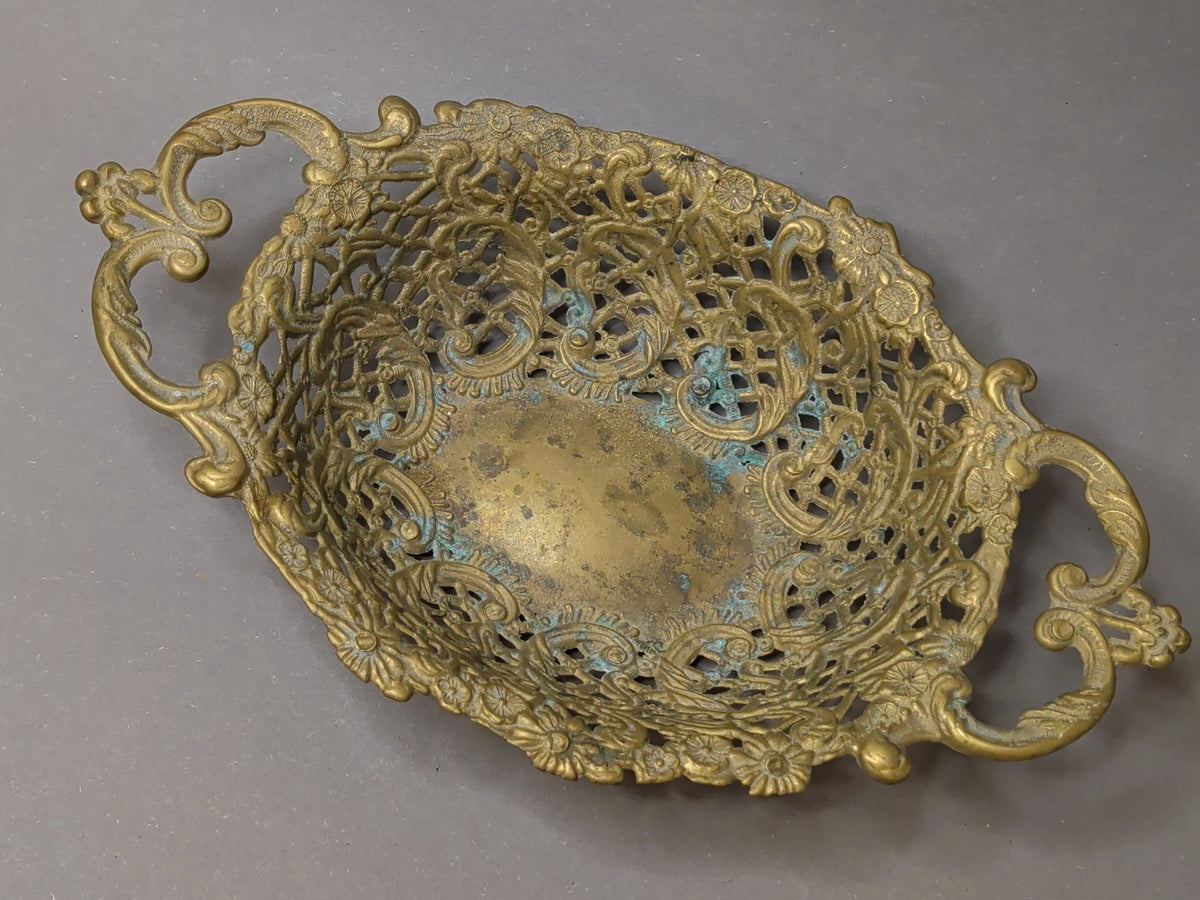 Draufsicht in die Messingschale: Rand aus Gitterwerk, Rocaillen und Blütenrosetten, glatter Schalenboden mit fleckiger Patina und Grünspan