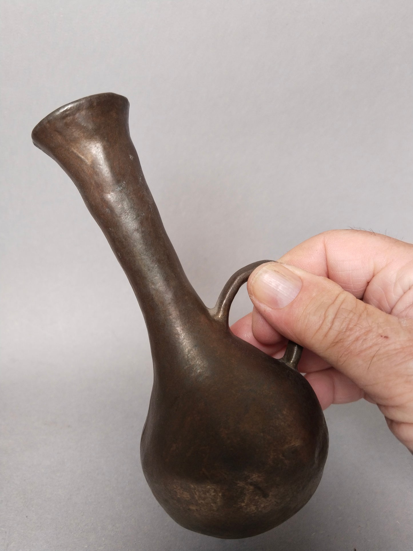 Eine Hand haelt die kleine skulpturale Brutalismus Vase am Henke