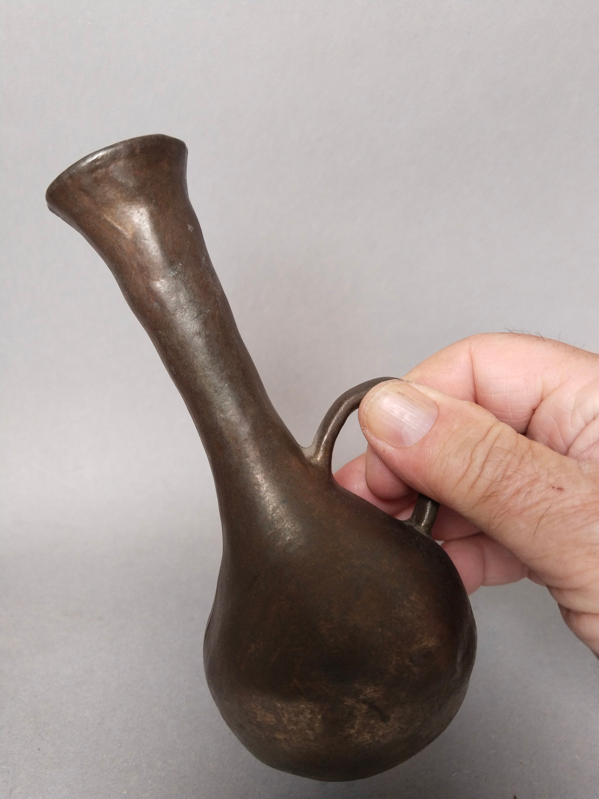 Eine Hand haelt die kleine skulpturale Brutalismus Vase am Henke