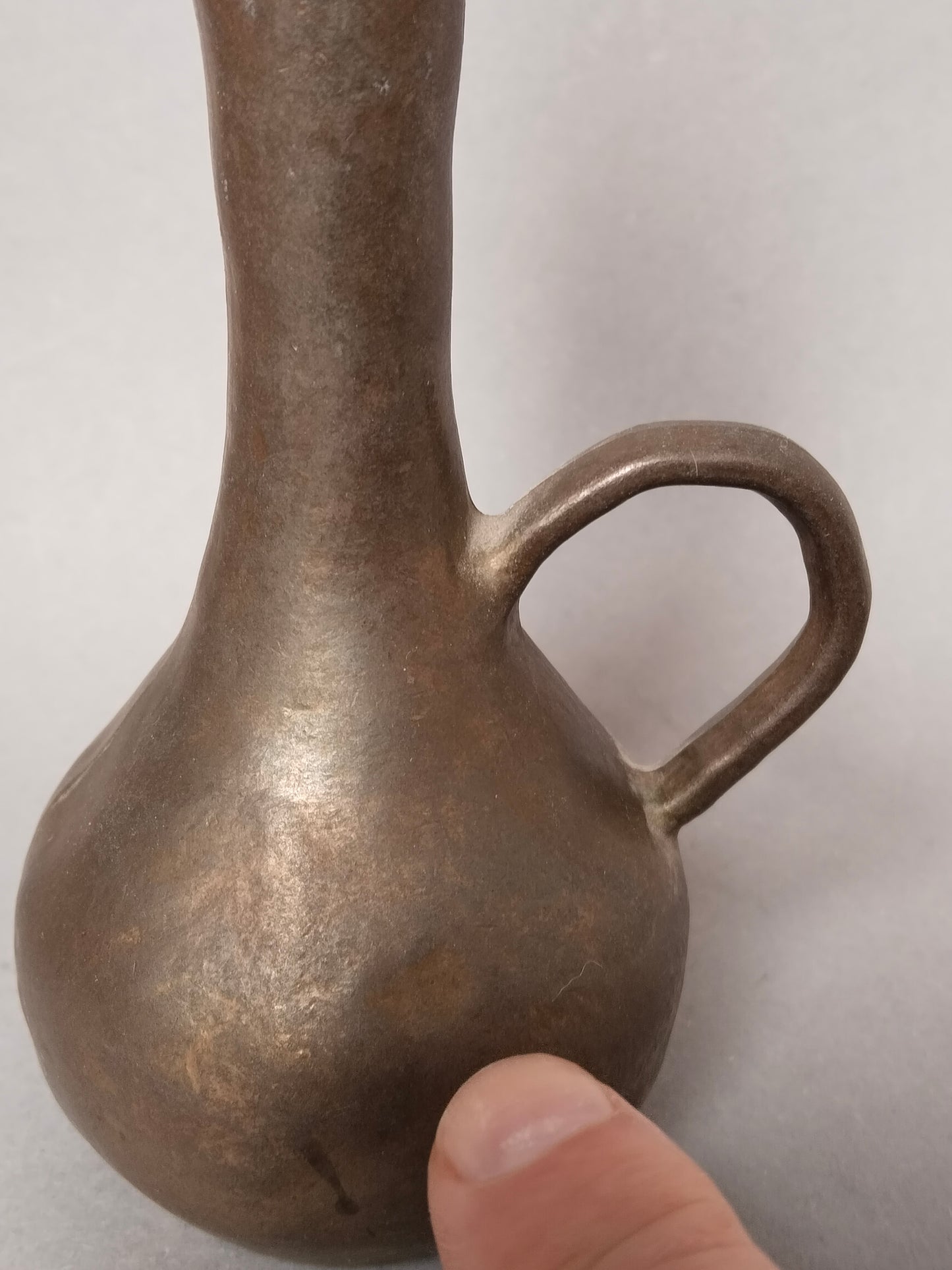 Ein Finger zeigt auf eine kleine ehrliche Vintage Delle am Bauch der Vase