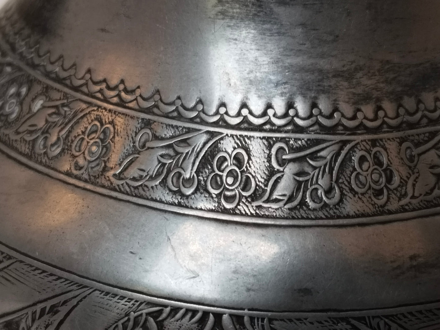 Nahaufnahme der oberen Zierbordüre mit floralem Rankenmuster, versilbertes Metall
