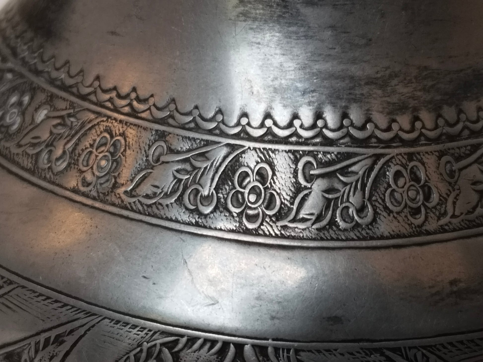 Nahaufnahme der oberen Zierbordüre mit floralem Rankenmuster, versilbertes Metall
