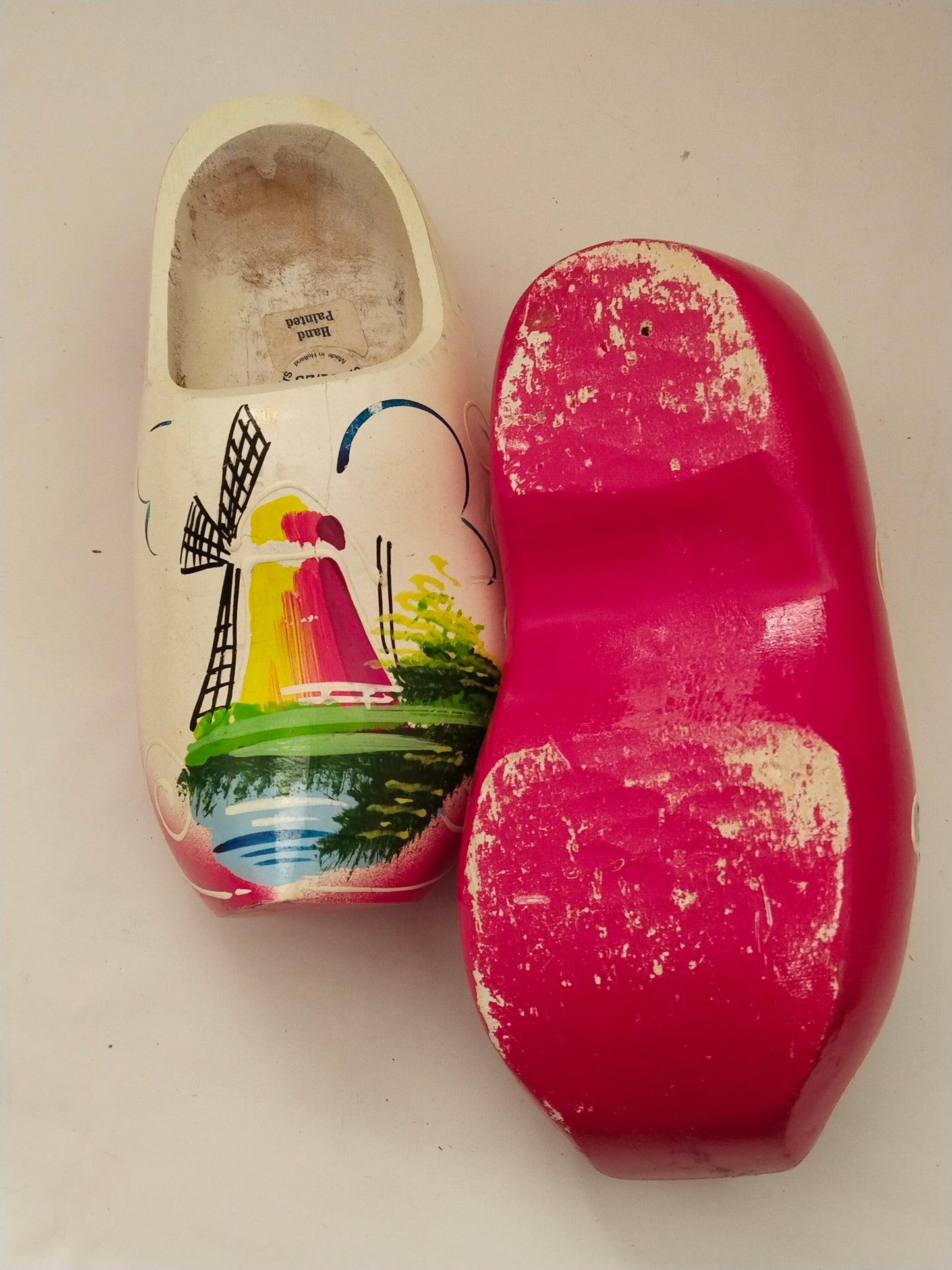 Handbemalte niederländische Holzschuhe Vintage. 2 Schuhe gleichzeitig auf einem Bbild. Ein Schuh von oben aufgenommen, der andere Schu mit der Unterseite.
