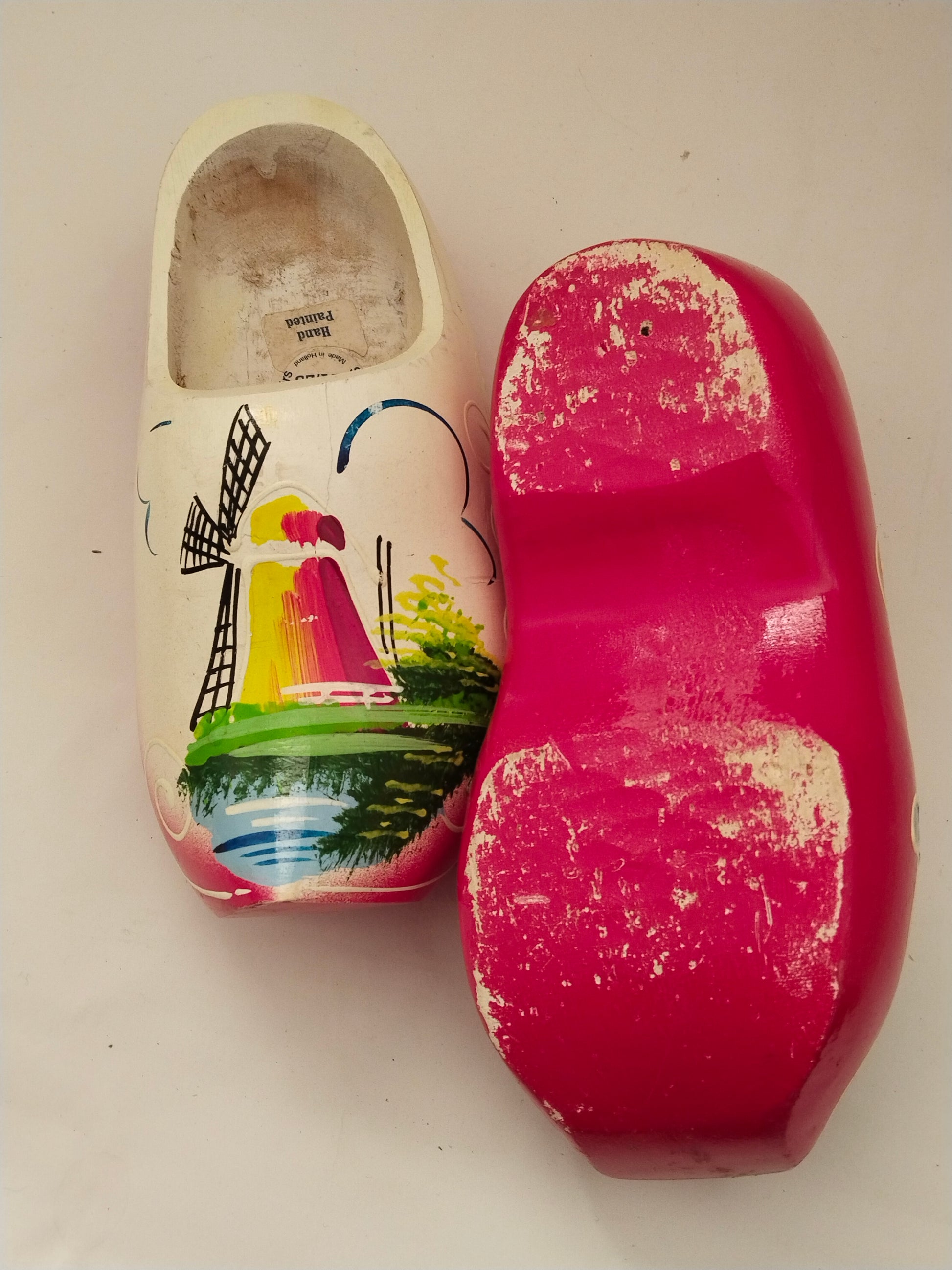Handbemalte niederländische Holzschuhe Vintage. 2 Schuhe gleichzeitig auf einem Bbild. Ein Schuh von oben aufgenommen, der andere Schu mit der Unterseite.