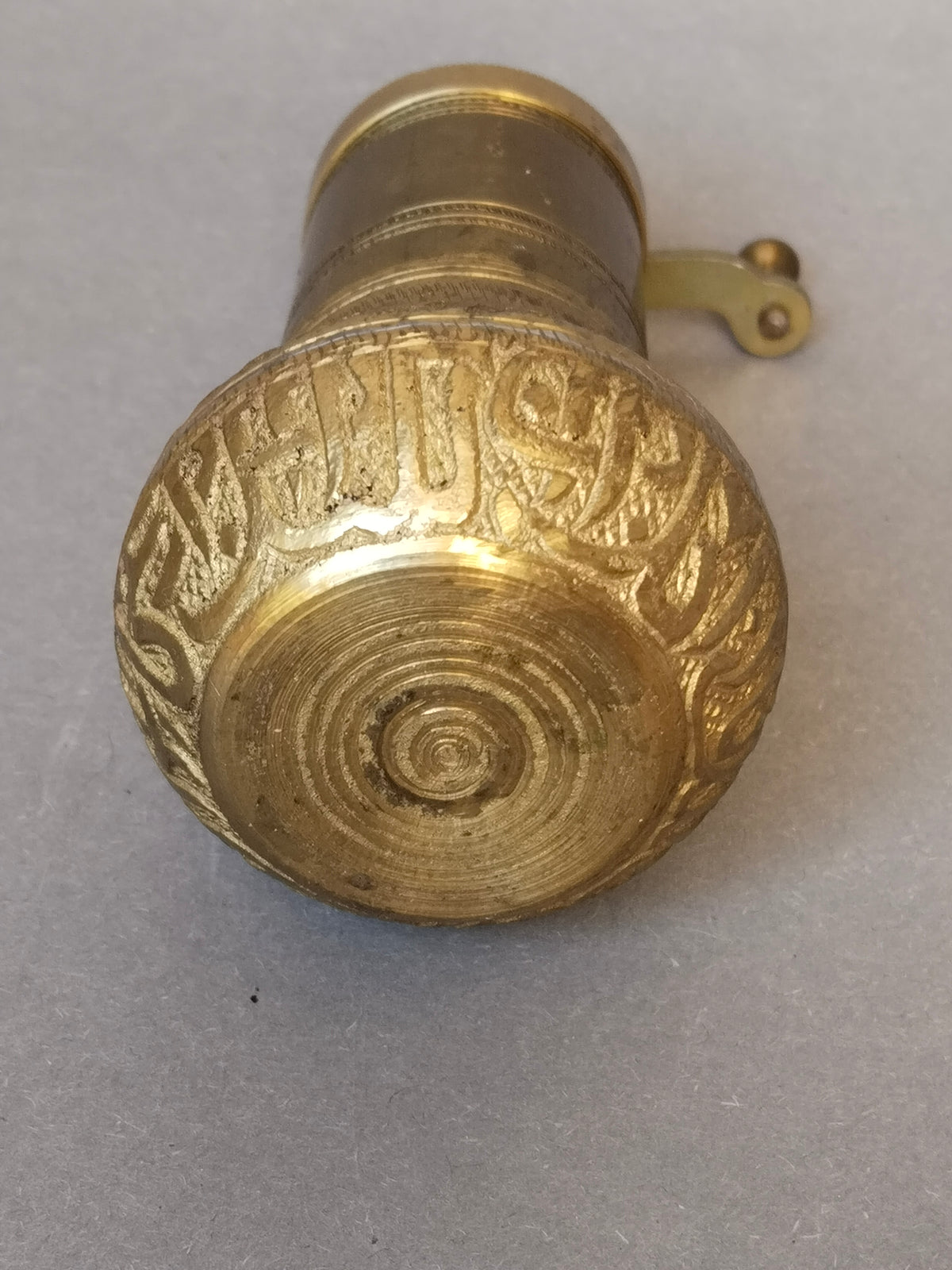 Unterseite der Pfeffermühle mit konzentrischen Drehrillen und umlaufender Gravur am Sockelrand
