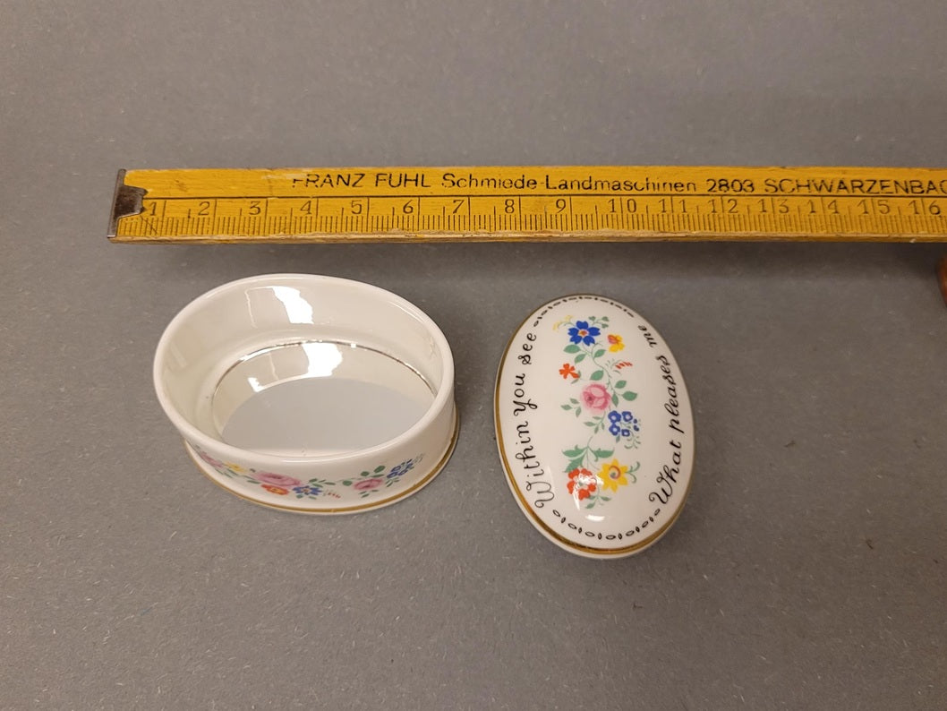 Ovale Pillendose aus weißem Bone China. Geöffnete Dose, daneben der Deckel. Ansicht von oben mit Lineal.