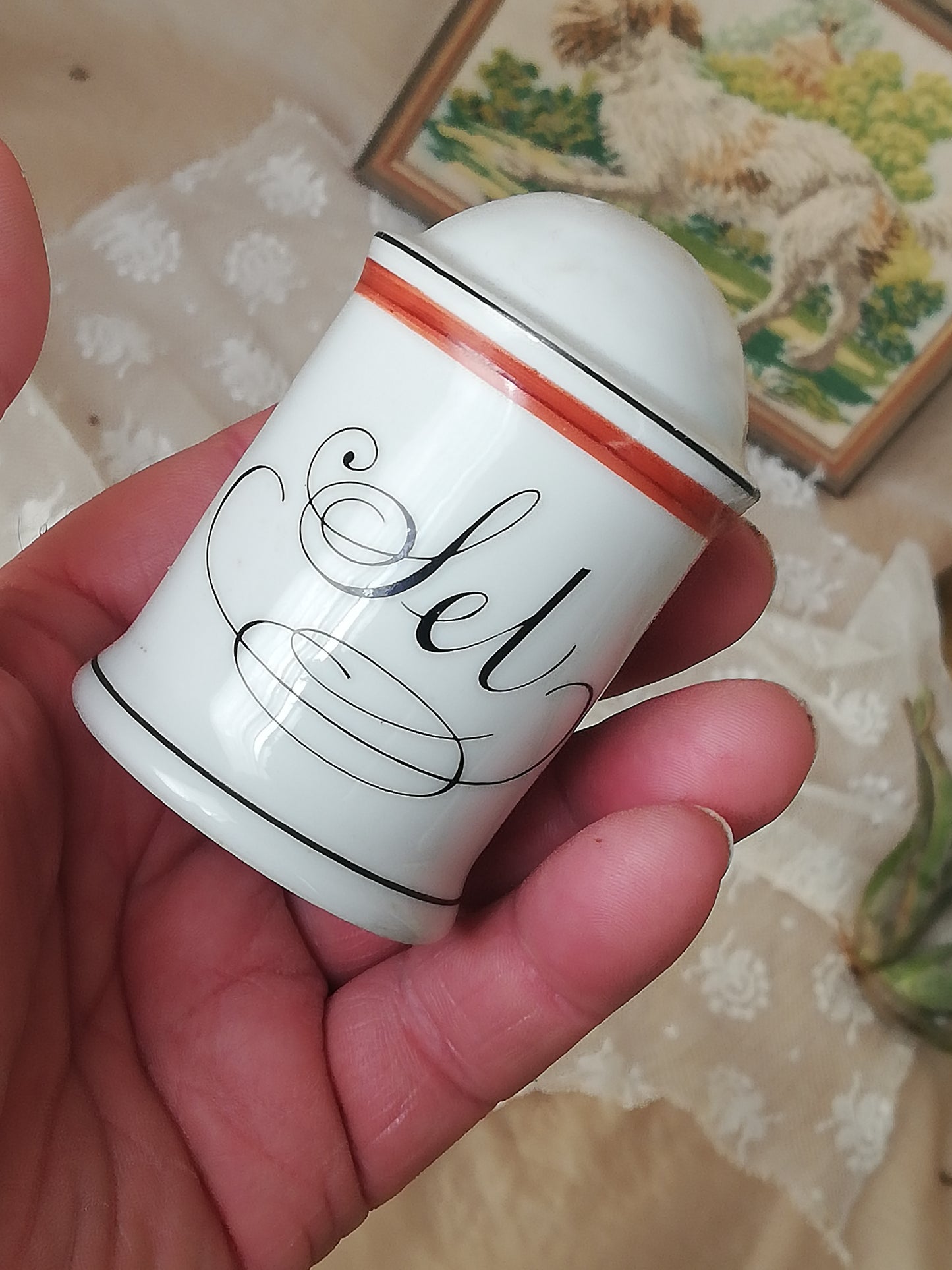 Kleiner Porzellansalzstreuer im französischen Design in eineer Hand zum Größenvergleich.