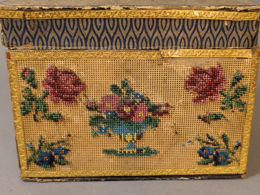 Vorderseite frontal: Fußschale mit Blüten, zwei rote Perlenrosen und blaue Blütenzweige, oben kleiner Einriss in der Goldbordüre