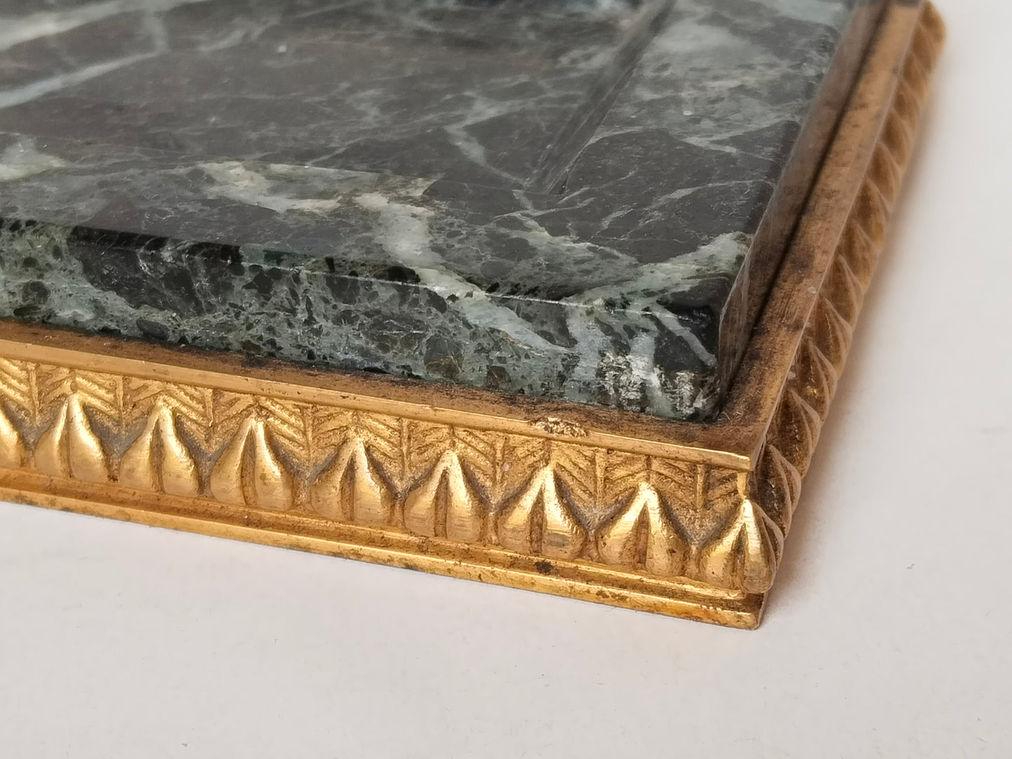 Detailaufnahme Ecke – Marmorkante und vergoldeter Ormolu-Lorbeerblatt-Fries, Verbindung Marmor und Metallbasis sichtbar
