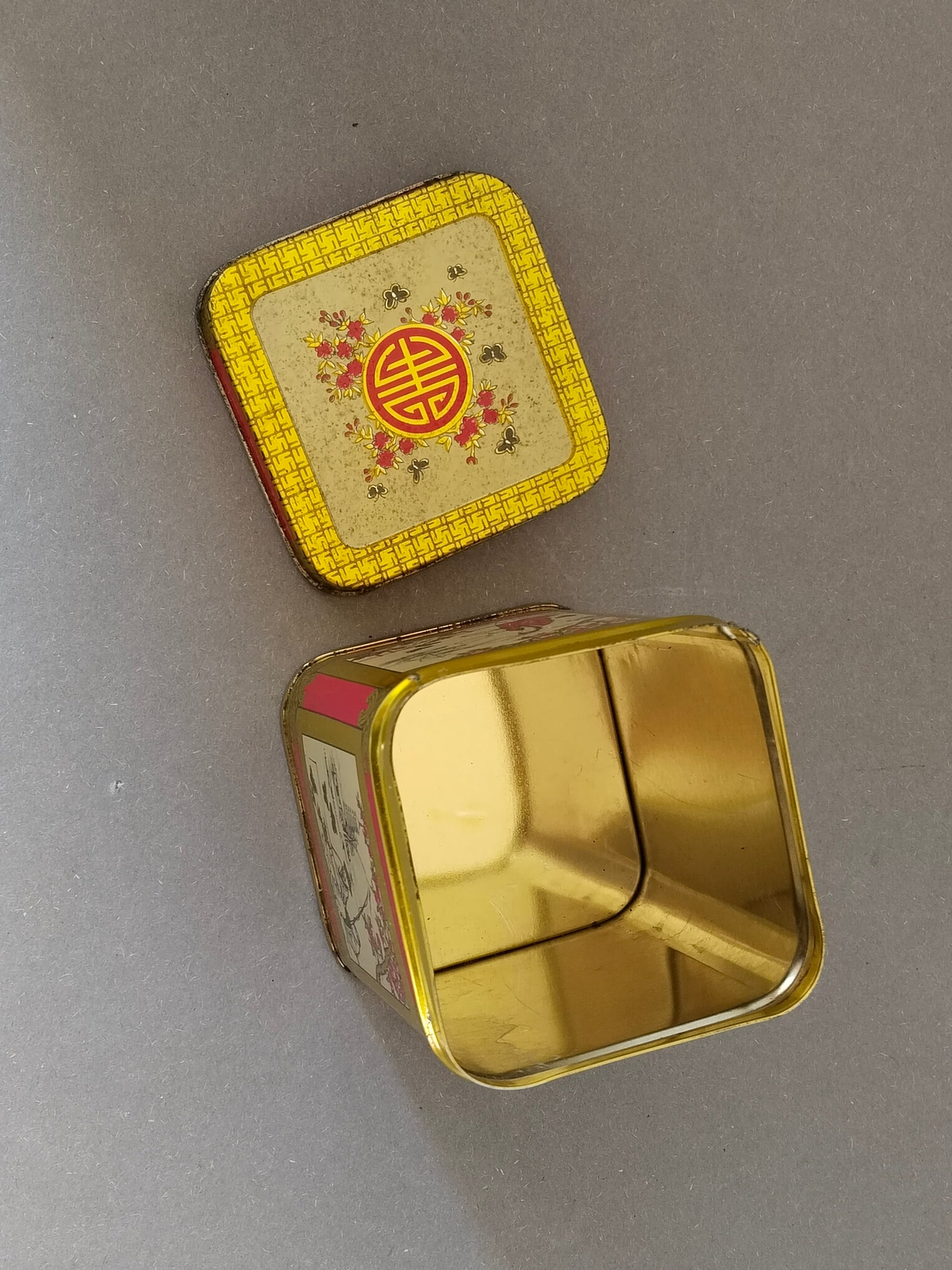 Geöffnete Blech-Teedose mit goldfarbenem, sauberem Innenraum und abgenommenem Deckel
