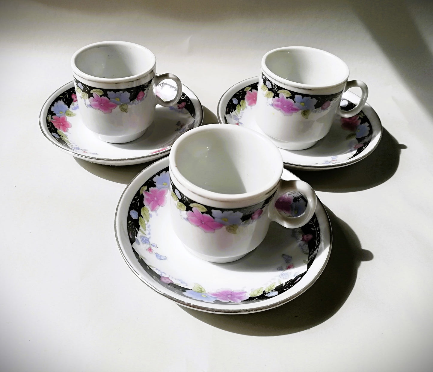 Sechsteiliges chinesisches Porzellan-Set mit bunten Blumenmotiven auf weißem Grund. 3 Tassen in einem Dreick angeordnet.