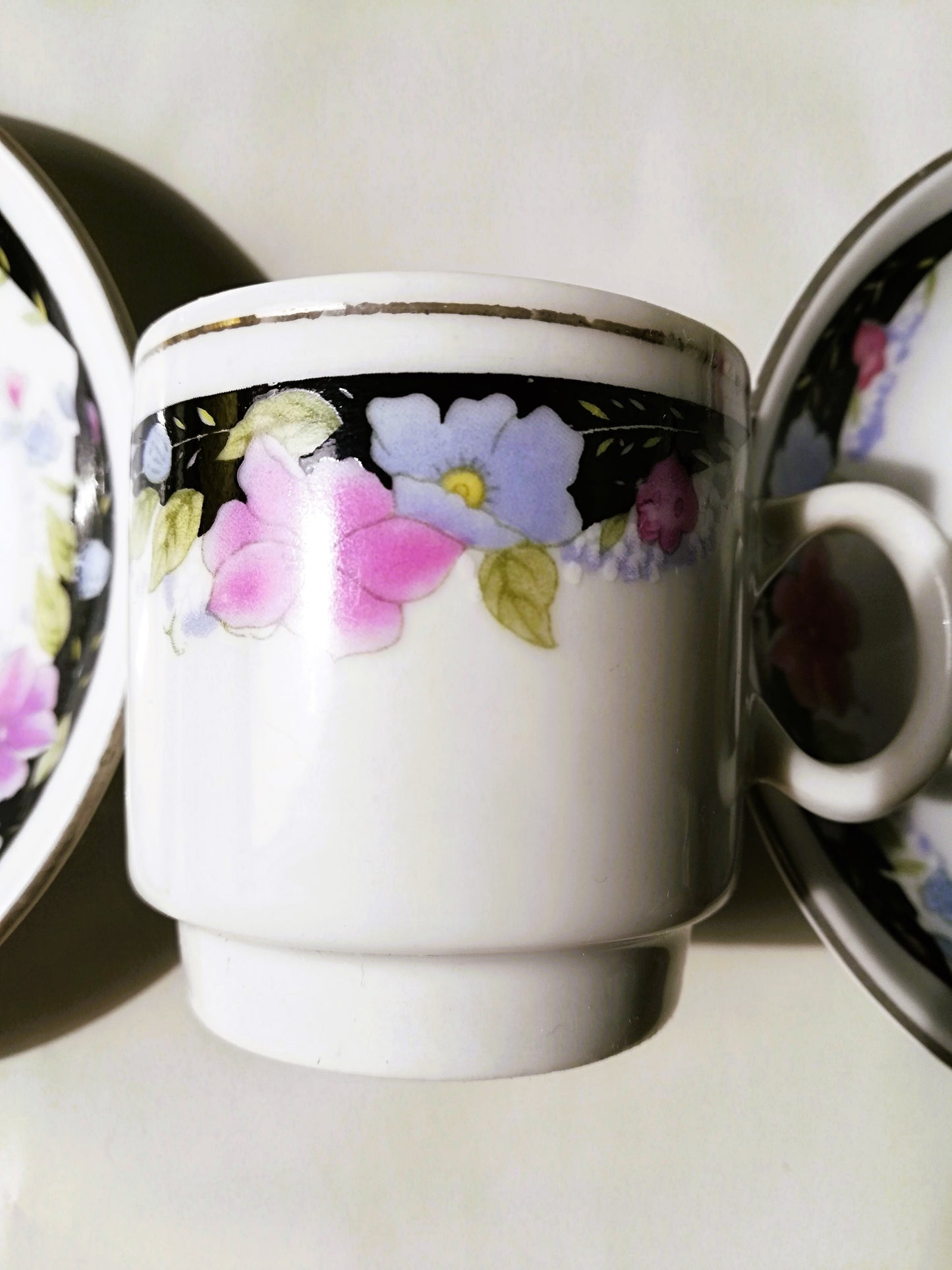 Sechsteiliges chinesisches Porzellan-Set mit bunten Blumenmotiven auf weißem Grund. Tasse zwischen 2 Tellern.