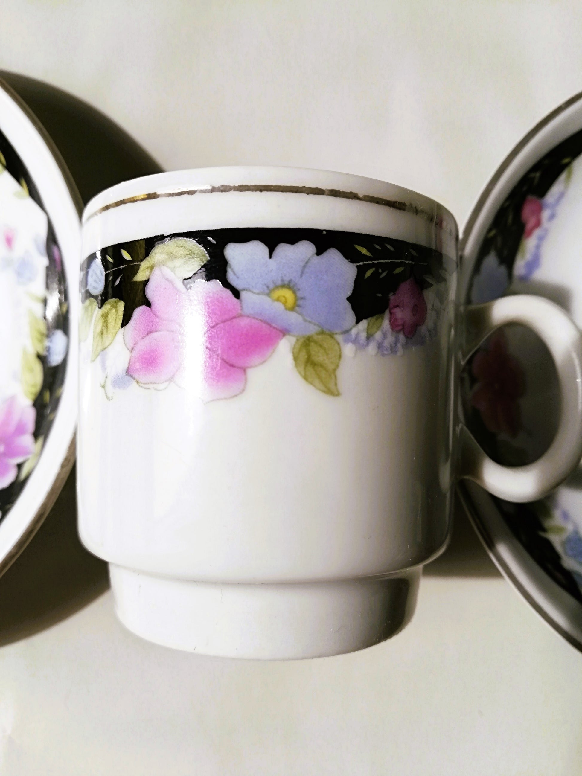 Sechsteiliges chinesisches Porzellan-Set mit bunten Blumenmotiven auf weißem Grund. Tasse zwischen 2 Tellern.